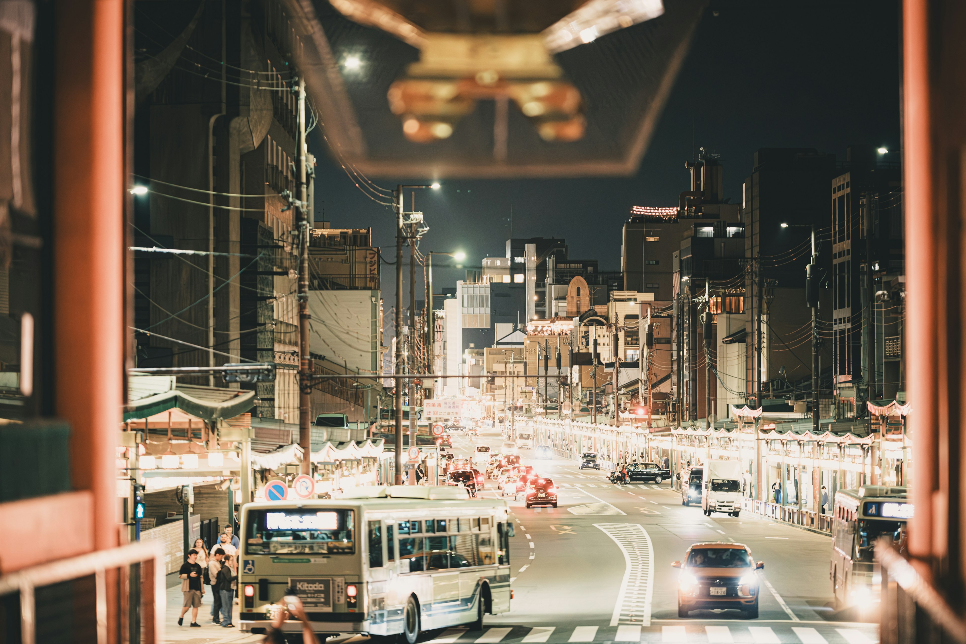 夜の街並みを映した写真 バスと車が通る通り 高層ビルとネオンの光