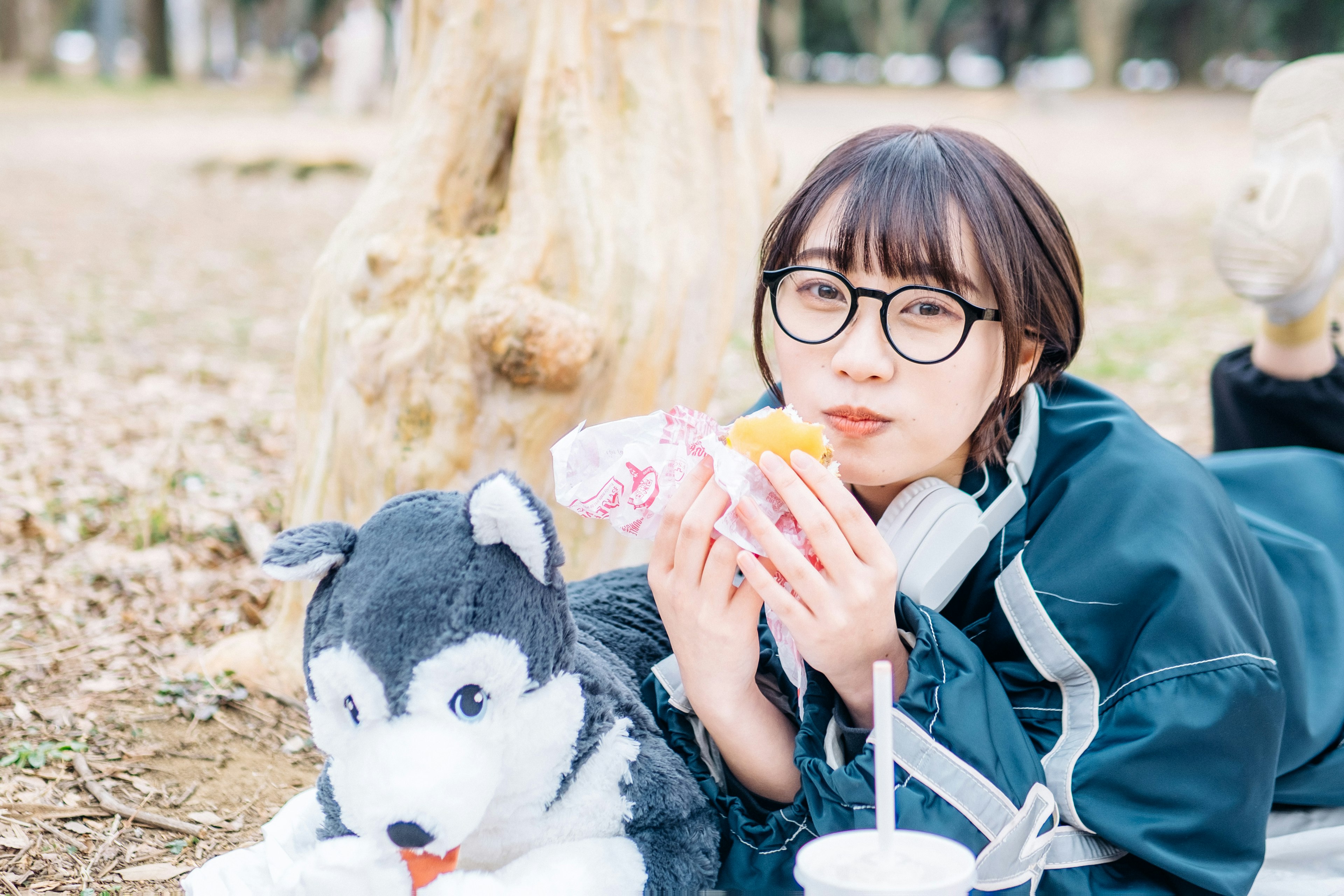 若い女性が公園でぬいぐるみの犬と一緒に食べ物を楽しんでいるシーン