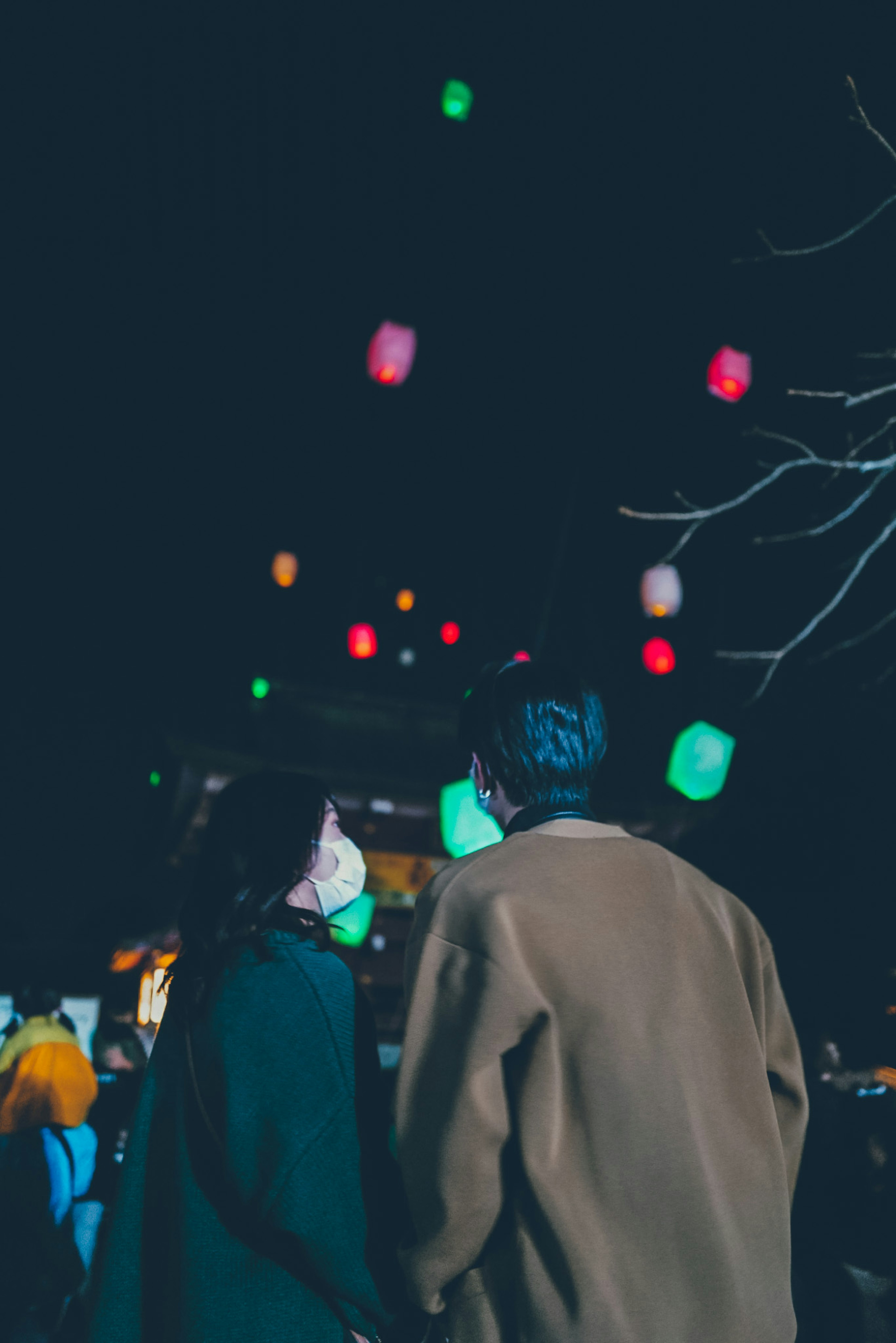 Pareja mirando linternas coloridas en el cielo nocturno