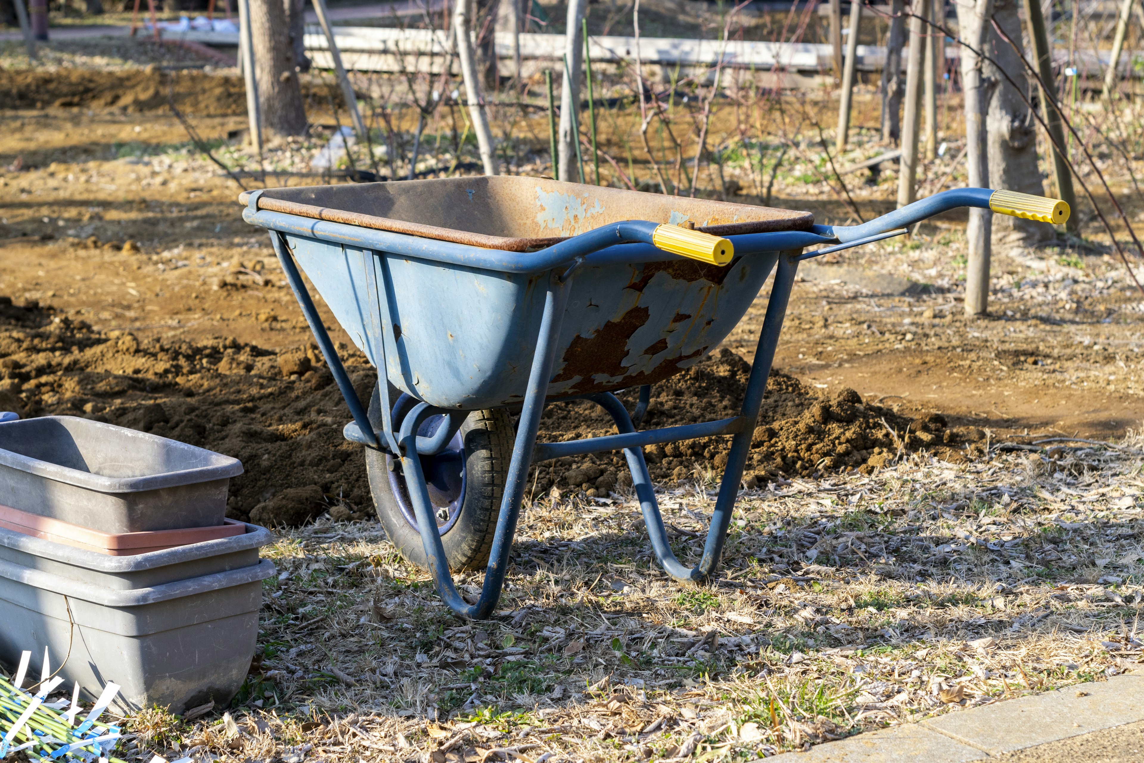 A blue wheelbarrow placed on the ground