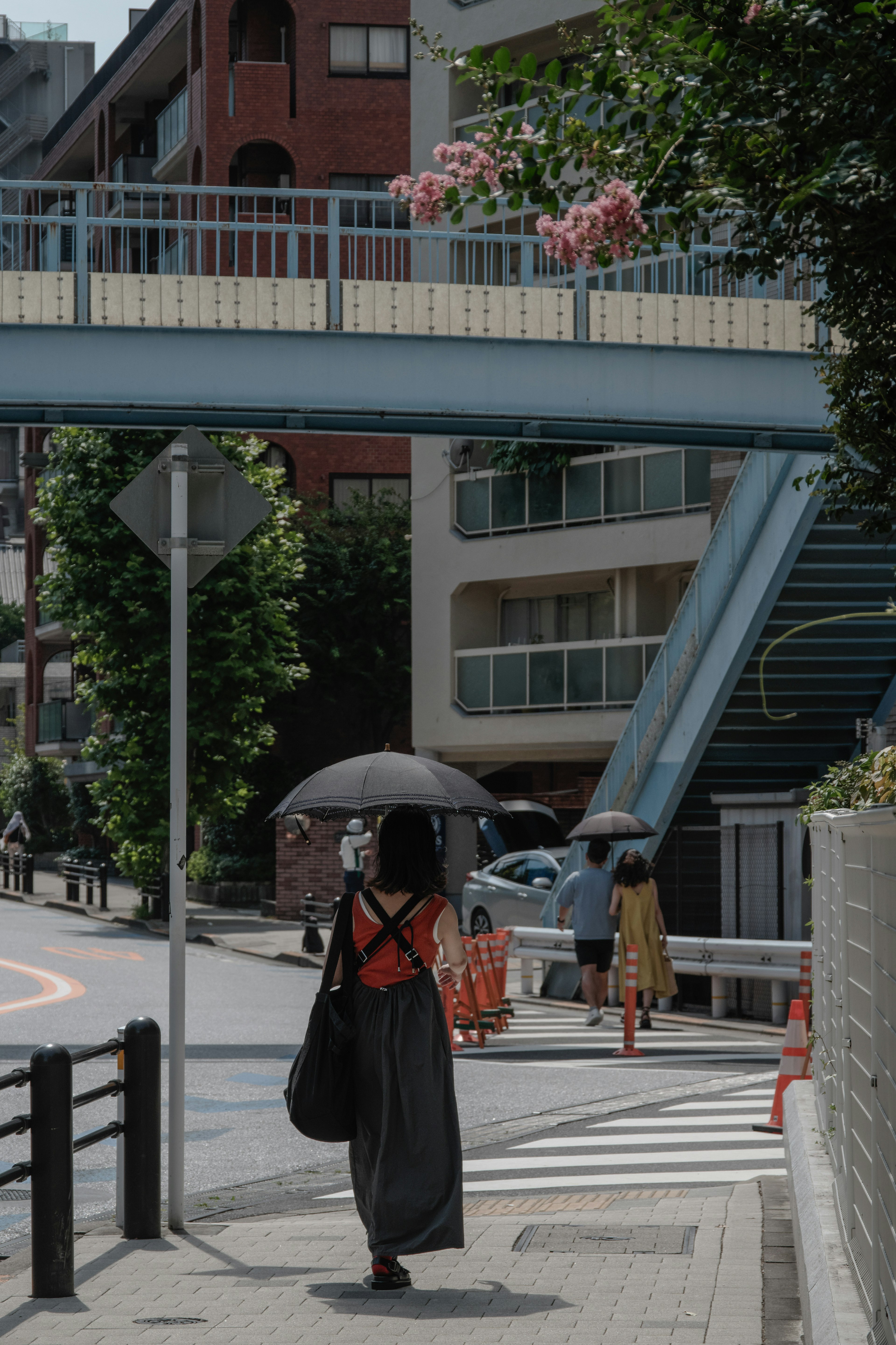 女性が傘をさして歩いている風景 橋と建物が背景にある