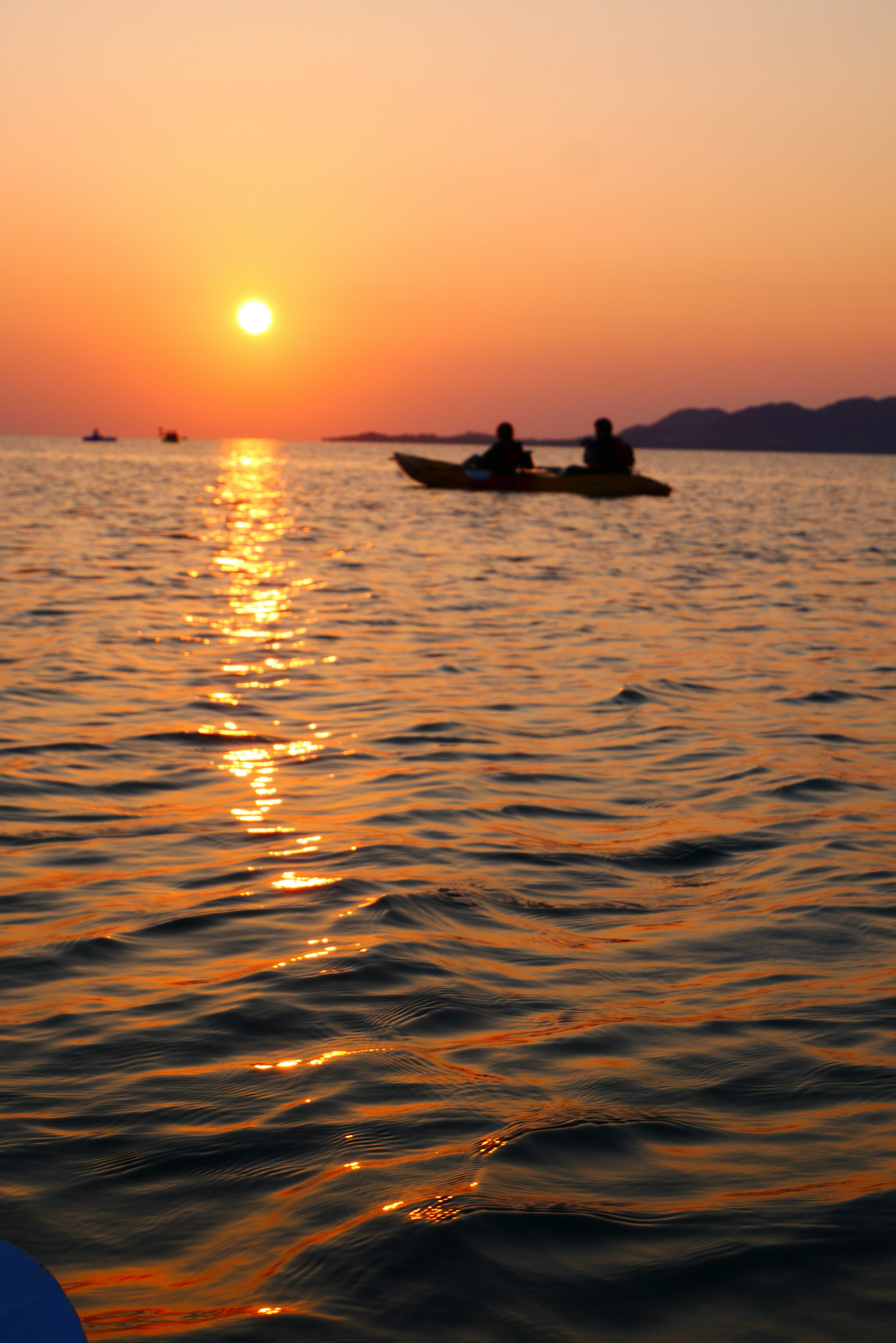 Silhouette von zwei Personen im Kajak auf dem Meer bei Sonnenuntergang