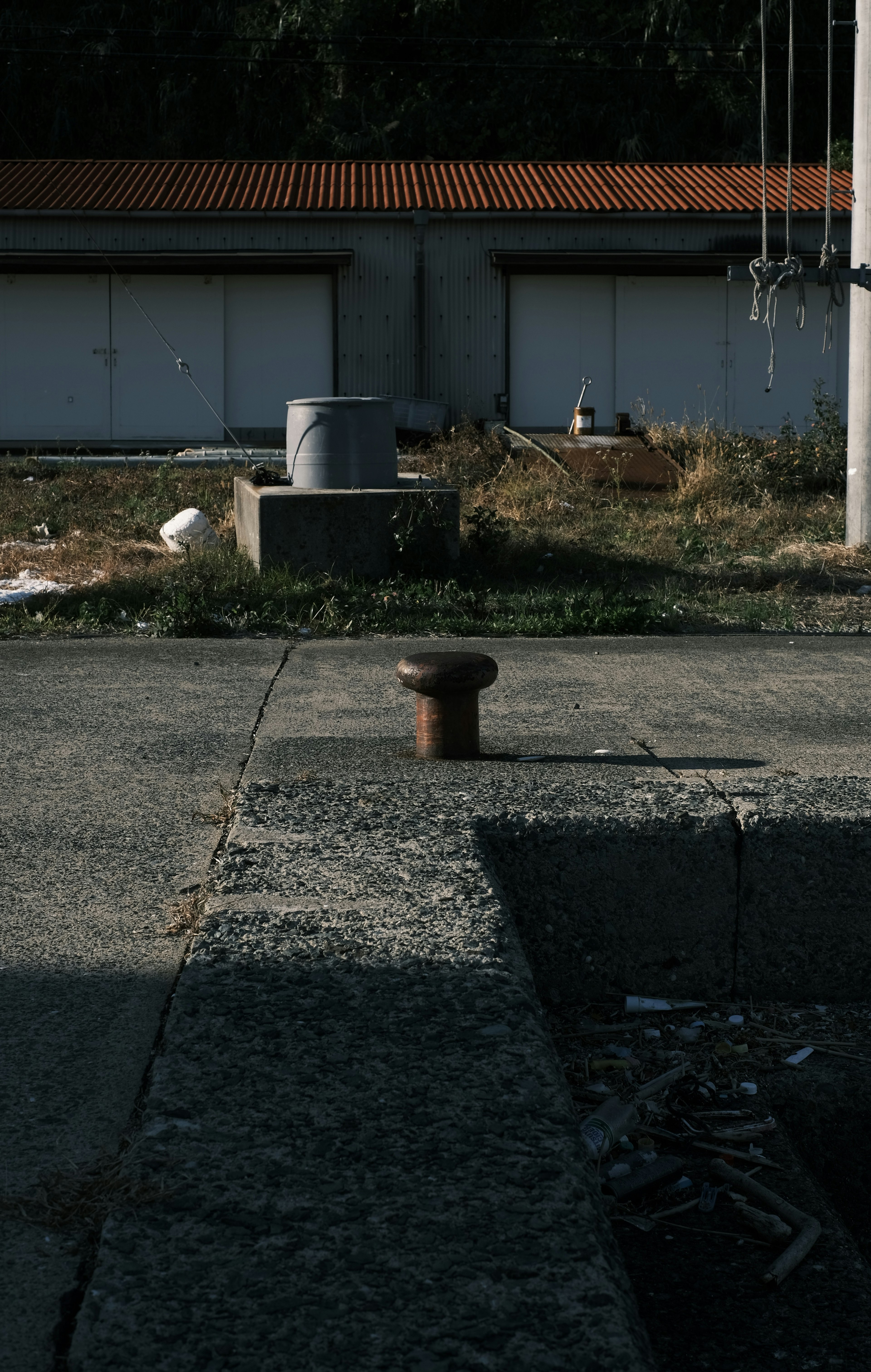 Bollard rond rouillé sur une surface en béton avec des bâtiments blancs en arrière-plan