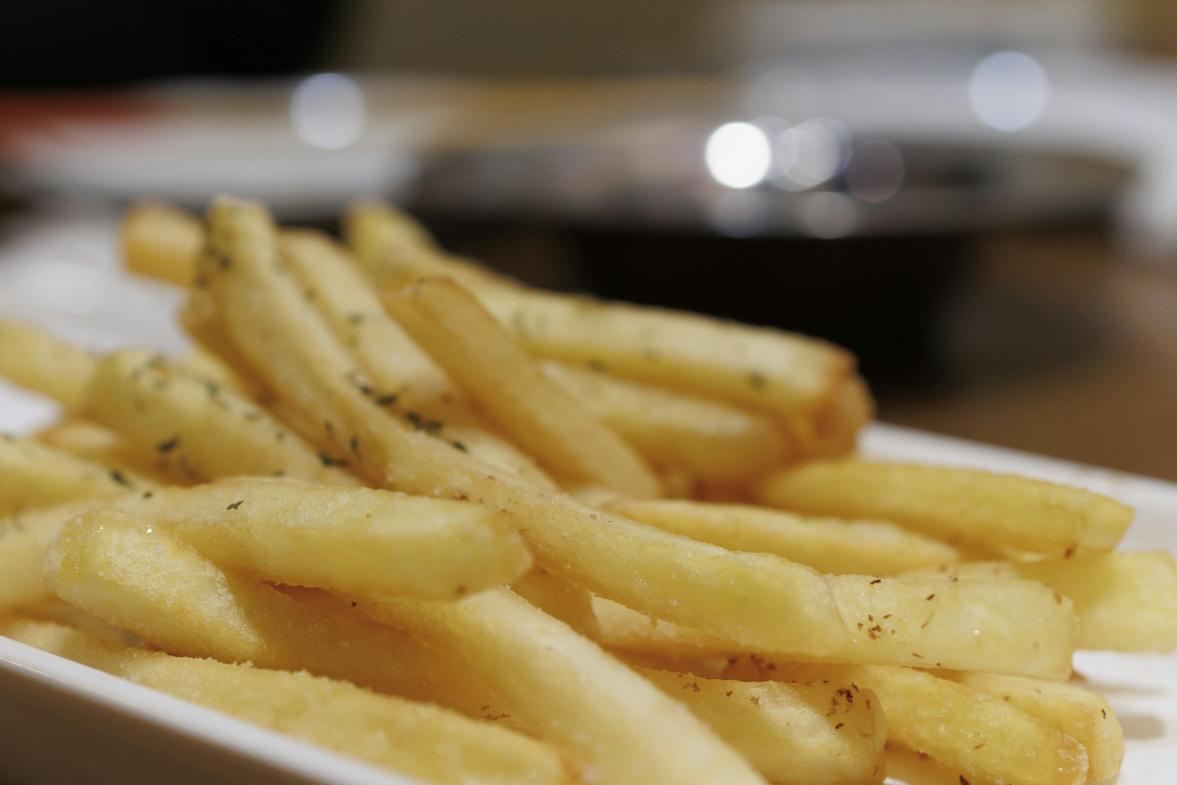 Crispy French fries served in a white dish with a blurred background