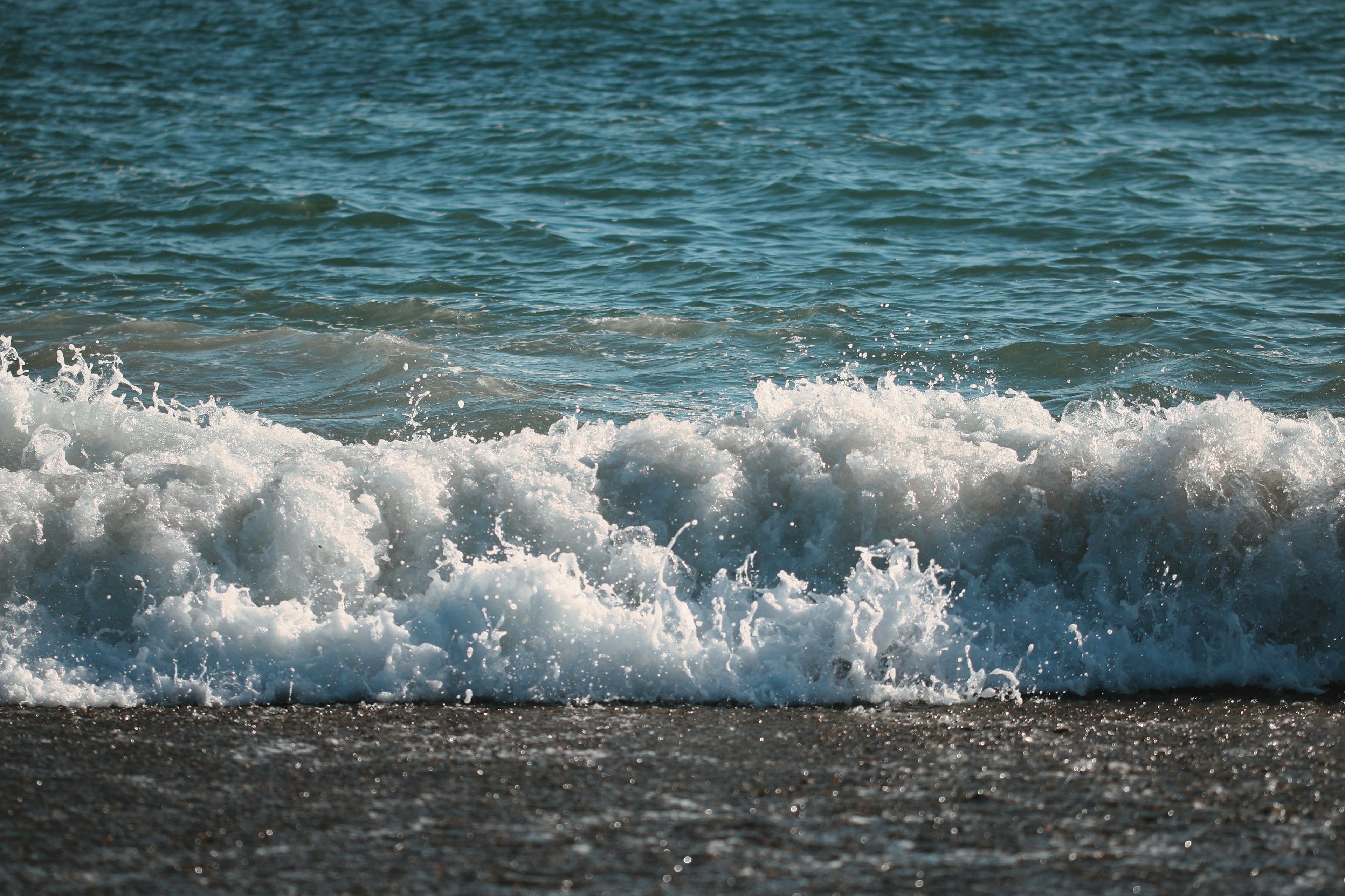 海浪拍打在沙灘上，清澈的藍色水面