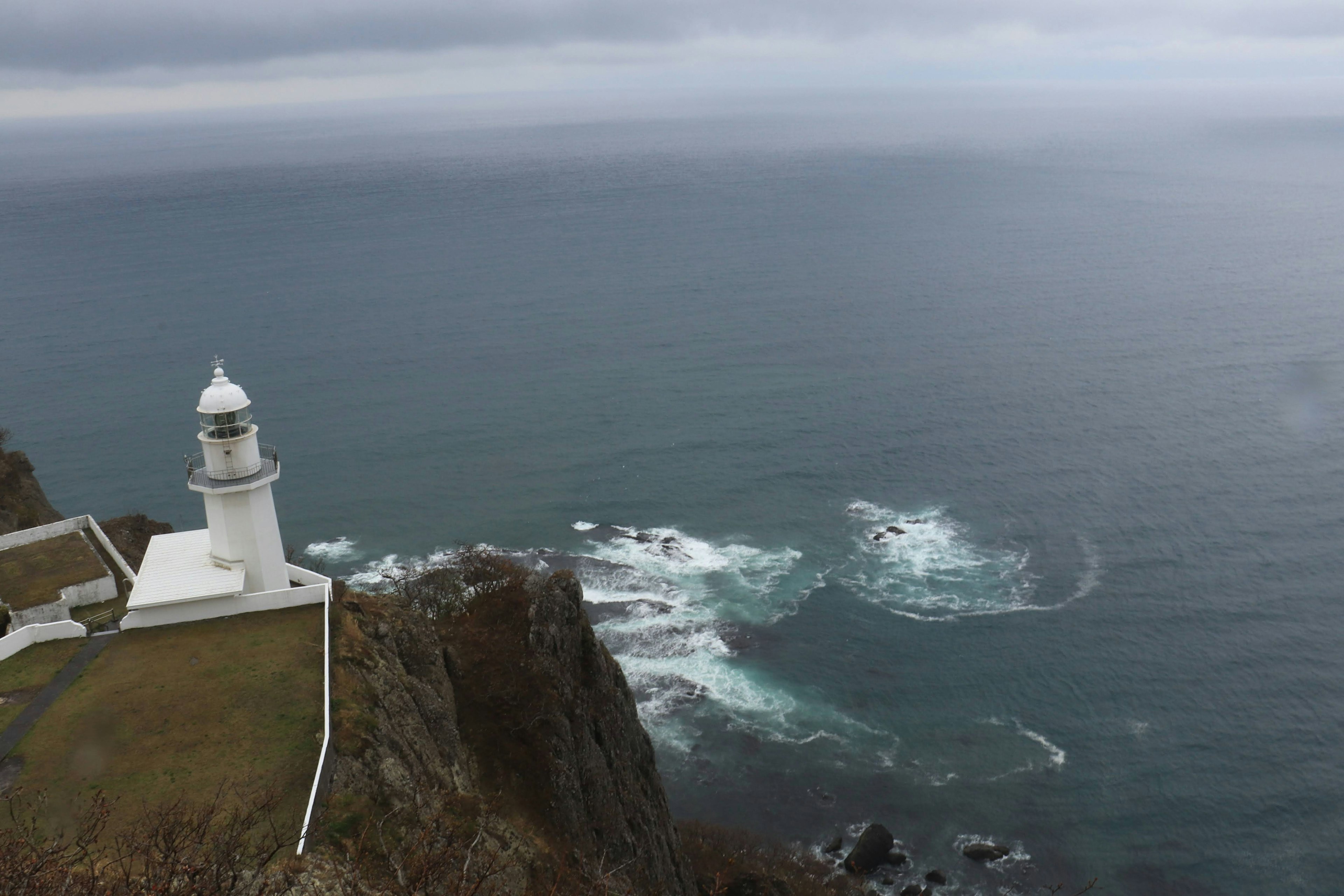 A white lighthouse perched on a cliff overlooking the ocean