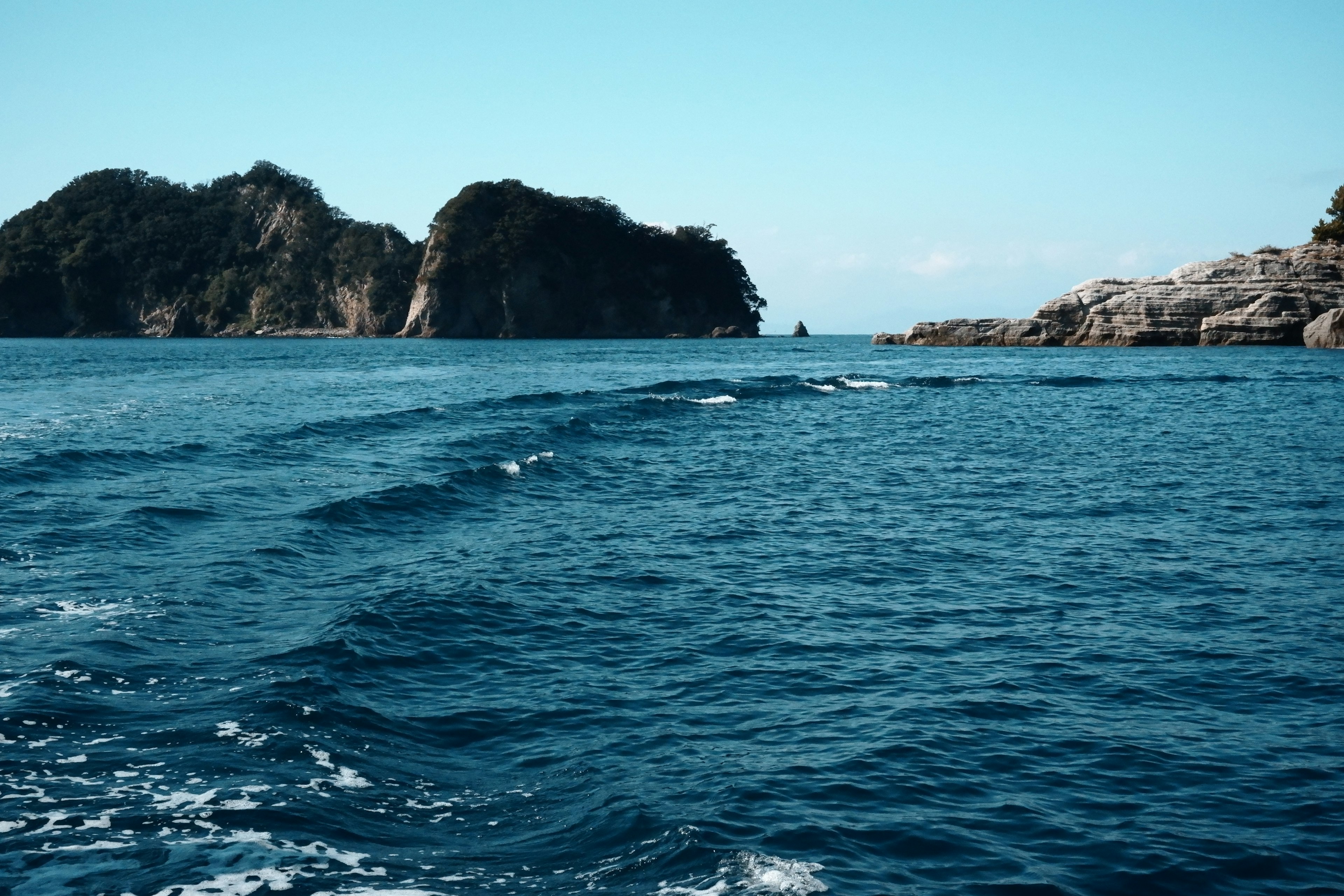 Pemandangan laut biru dengan pulau berbatu di latar belakang