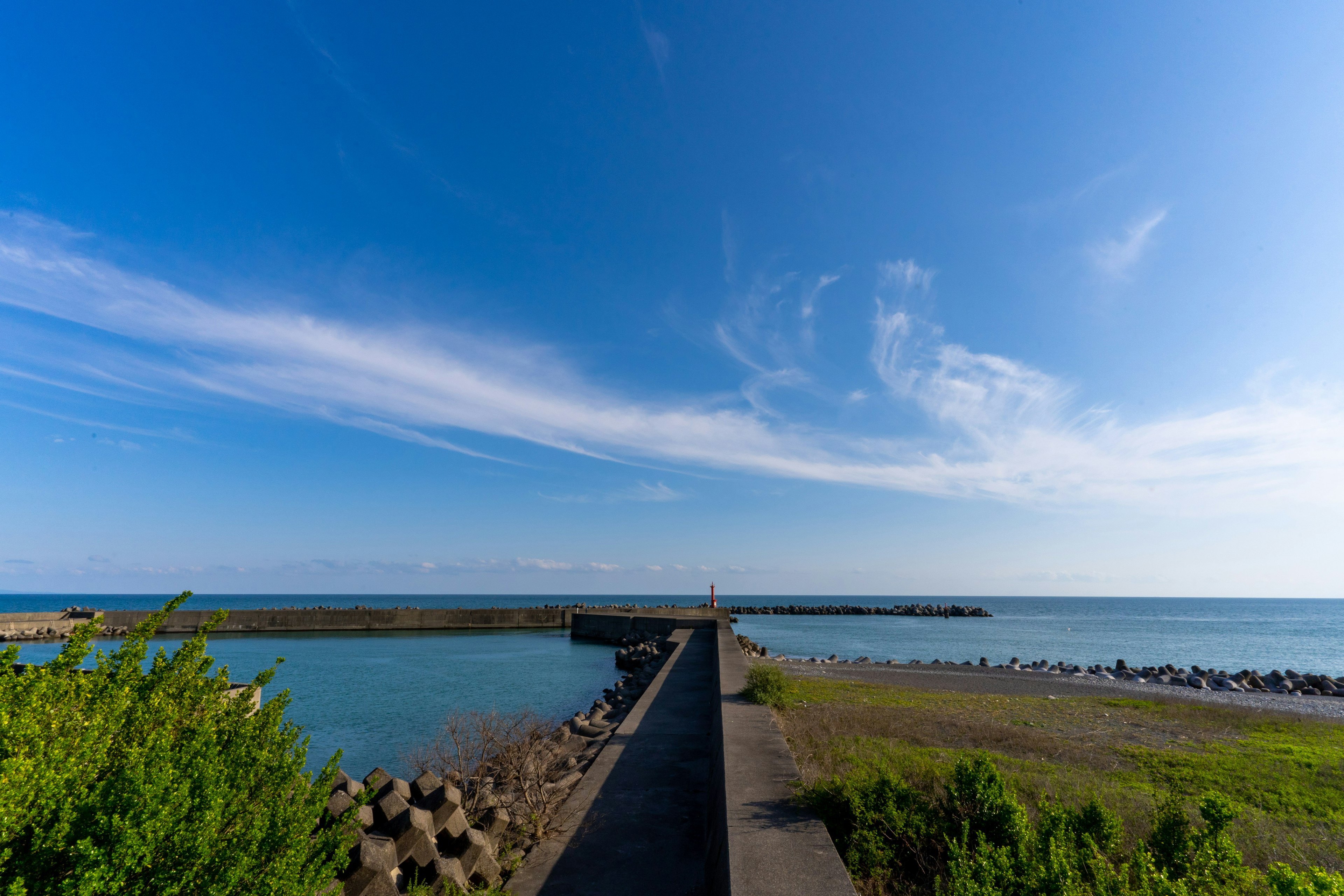 青空と海の景色を背景にした防波堤のパノラマビュー