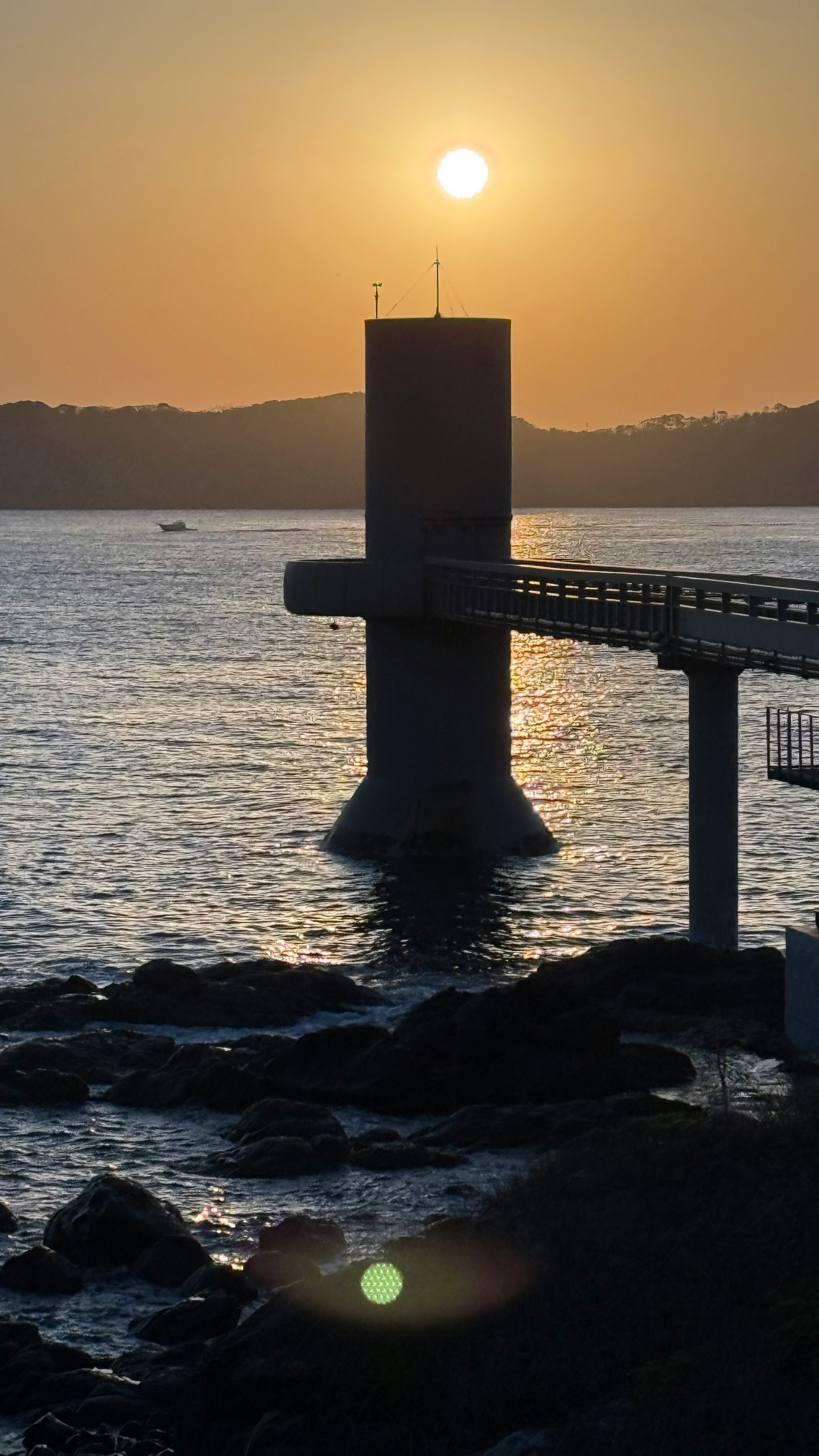 Sunset over a coastal pier with a supporting pillar