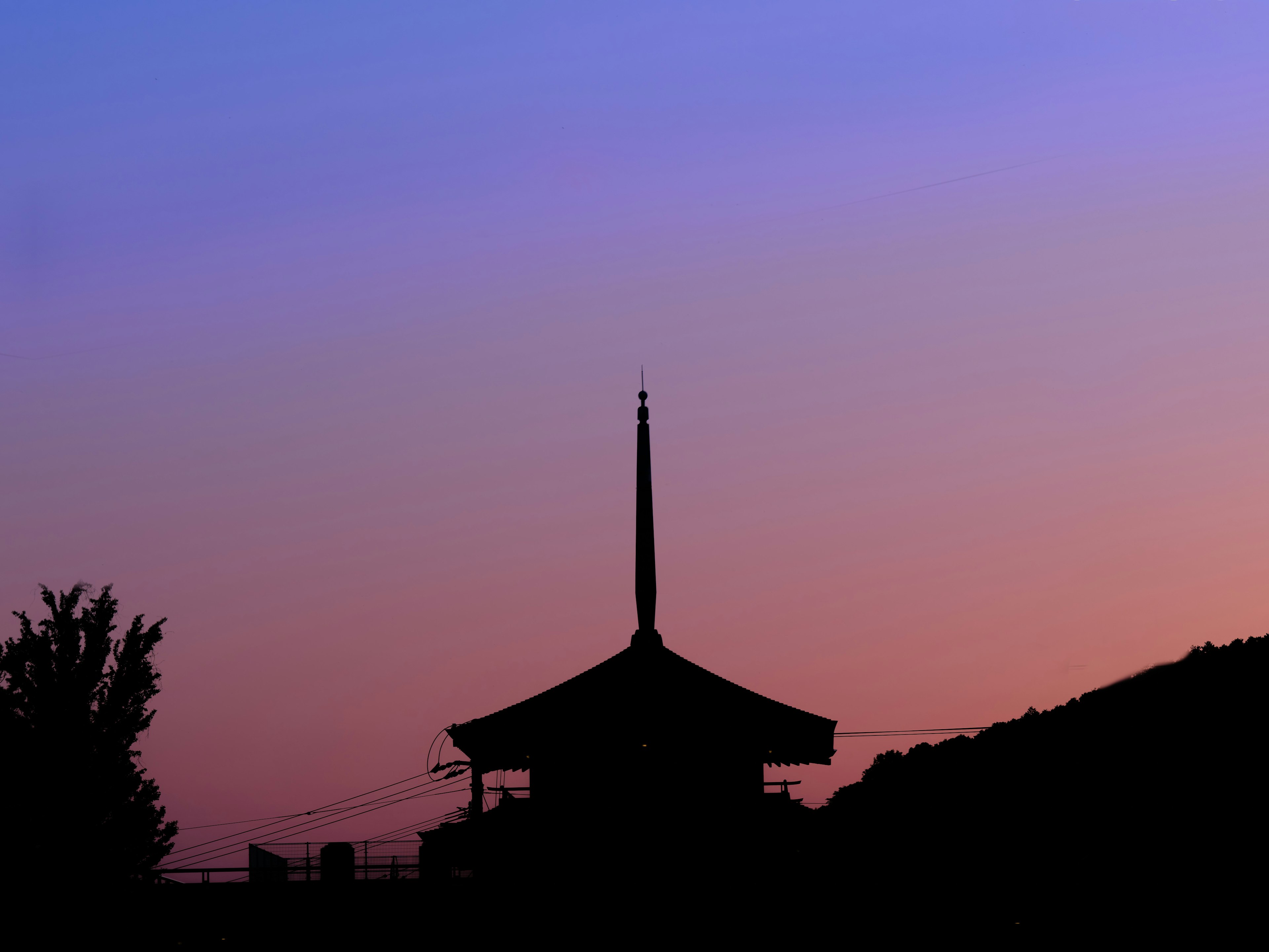 Silhouette bangunan di latar belakang langit bergradasi warna