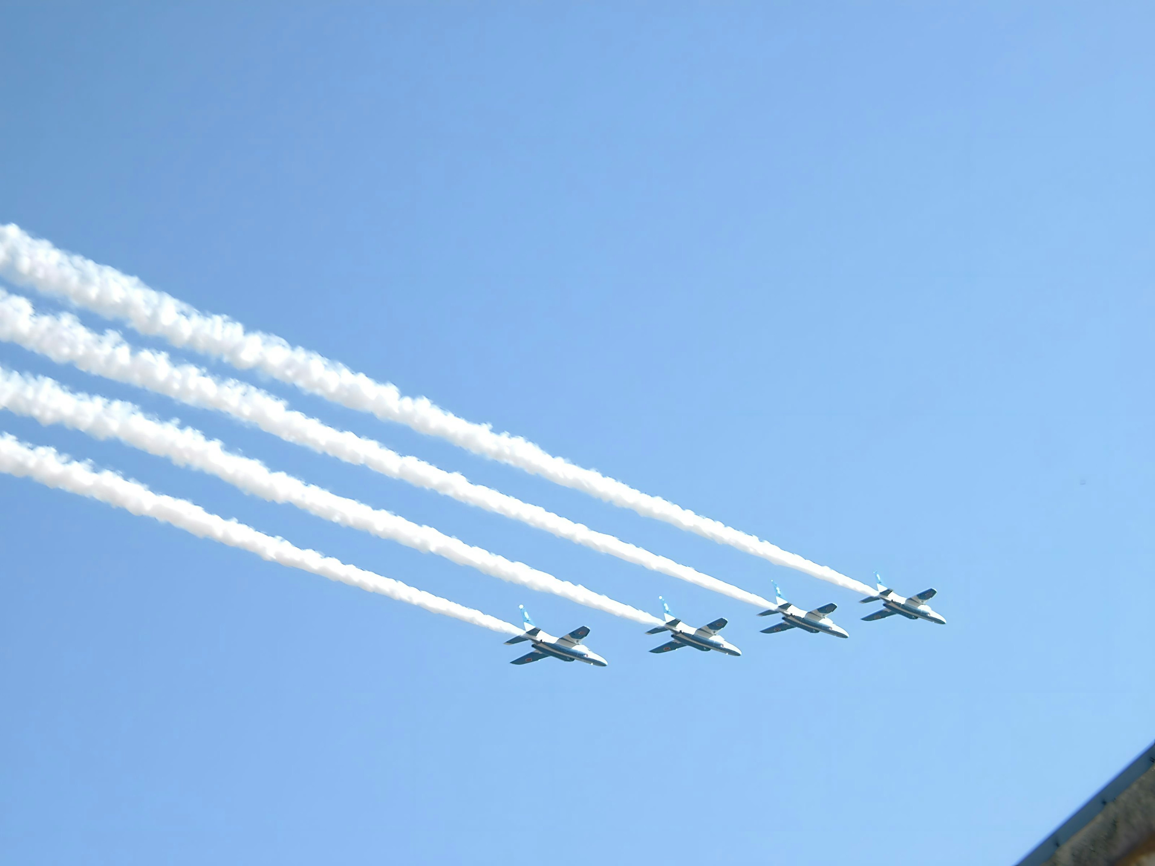 Cuatro aviones volando en un cielo azul dejando estelas blancas