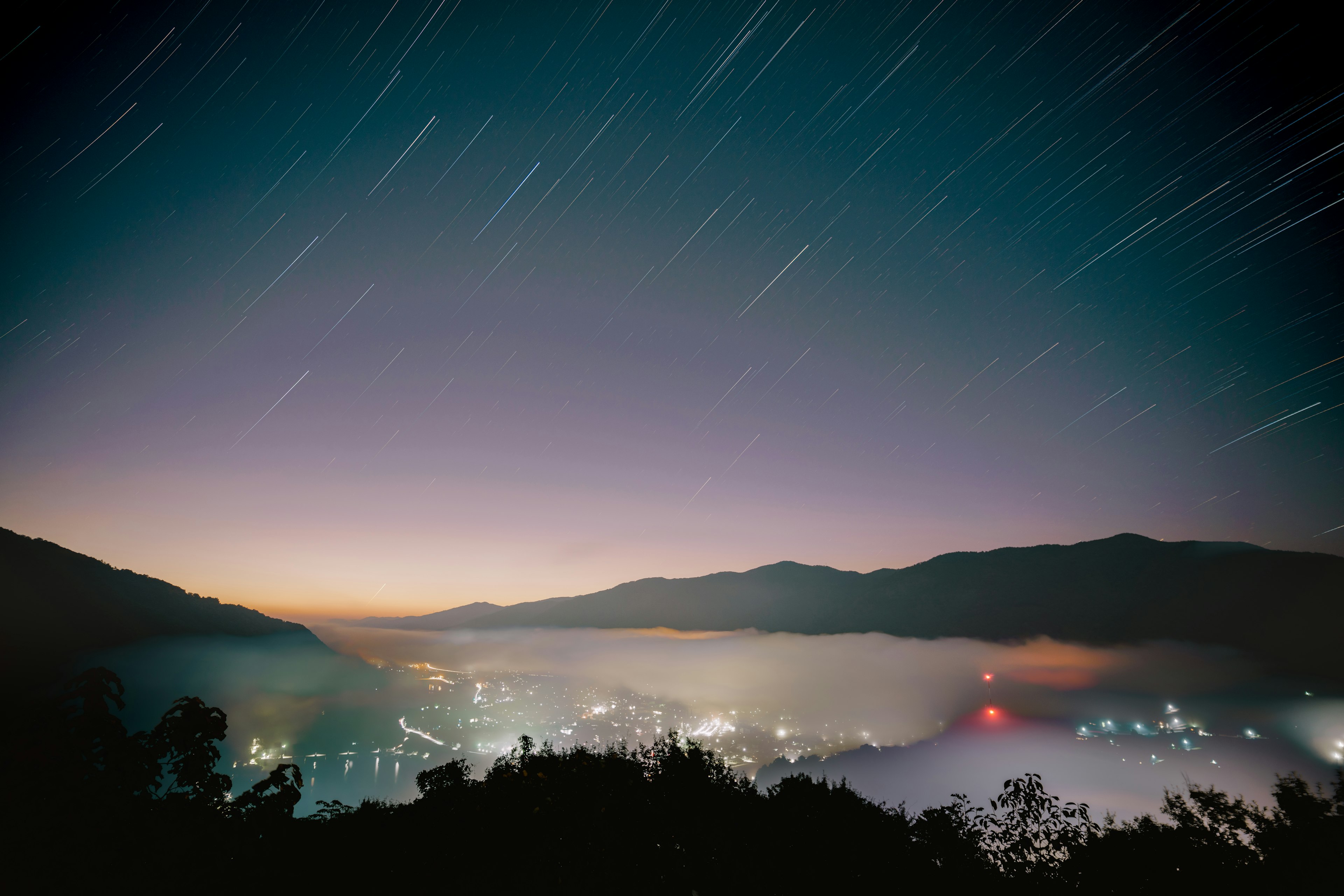 Night sky with star trails over mountains and a valley