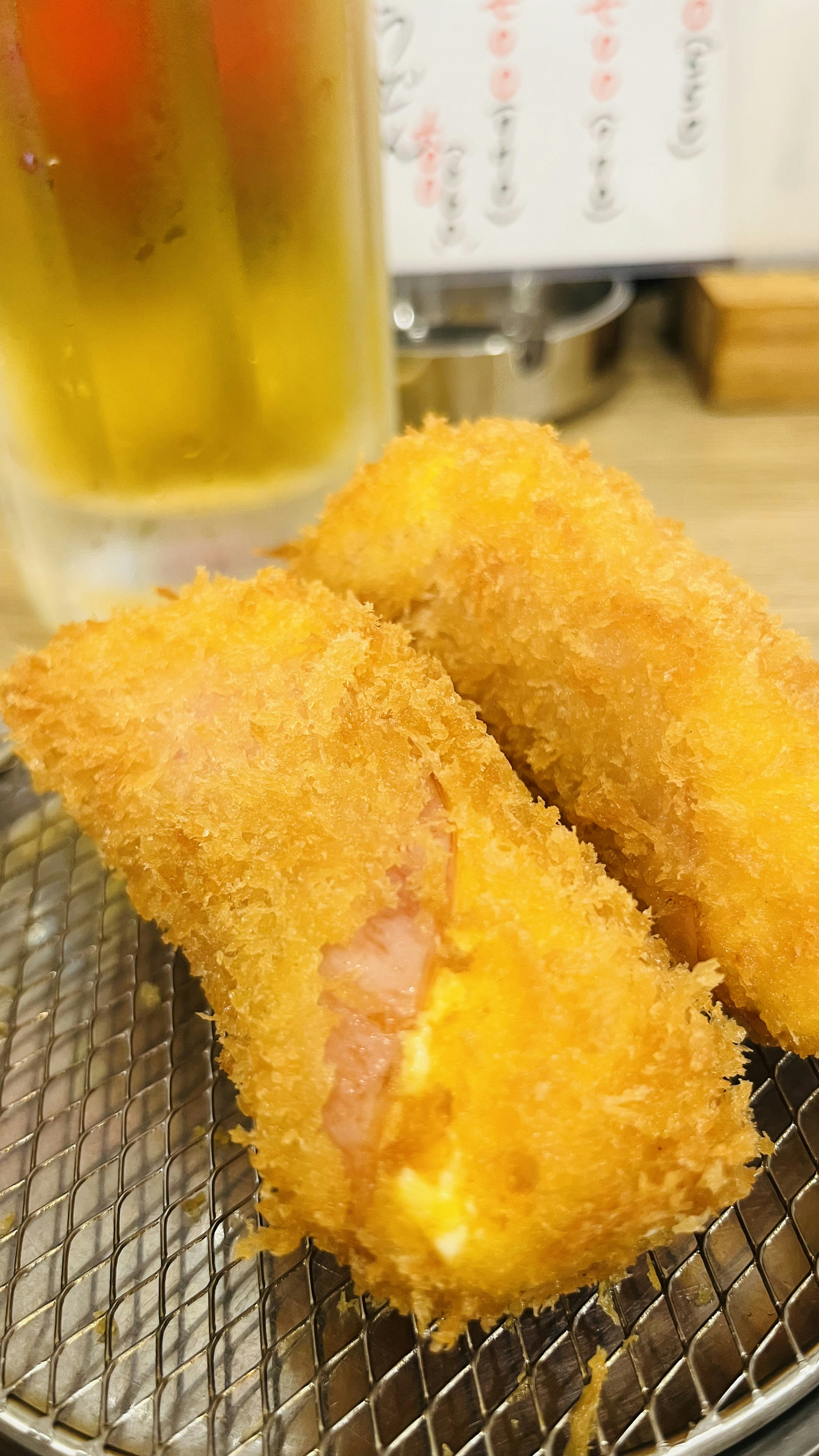 Goldbraune Kroketten auf einem Drahtgestell mit einem Glas Bier im Hintergrund