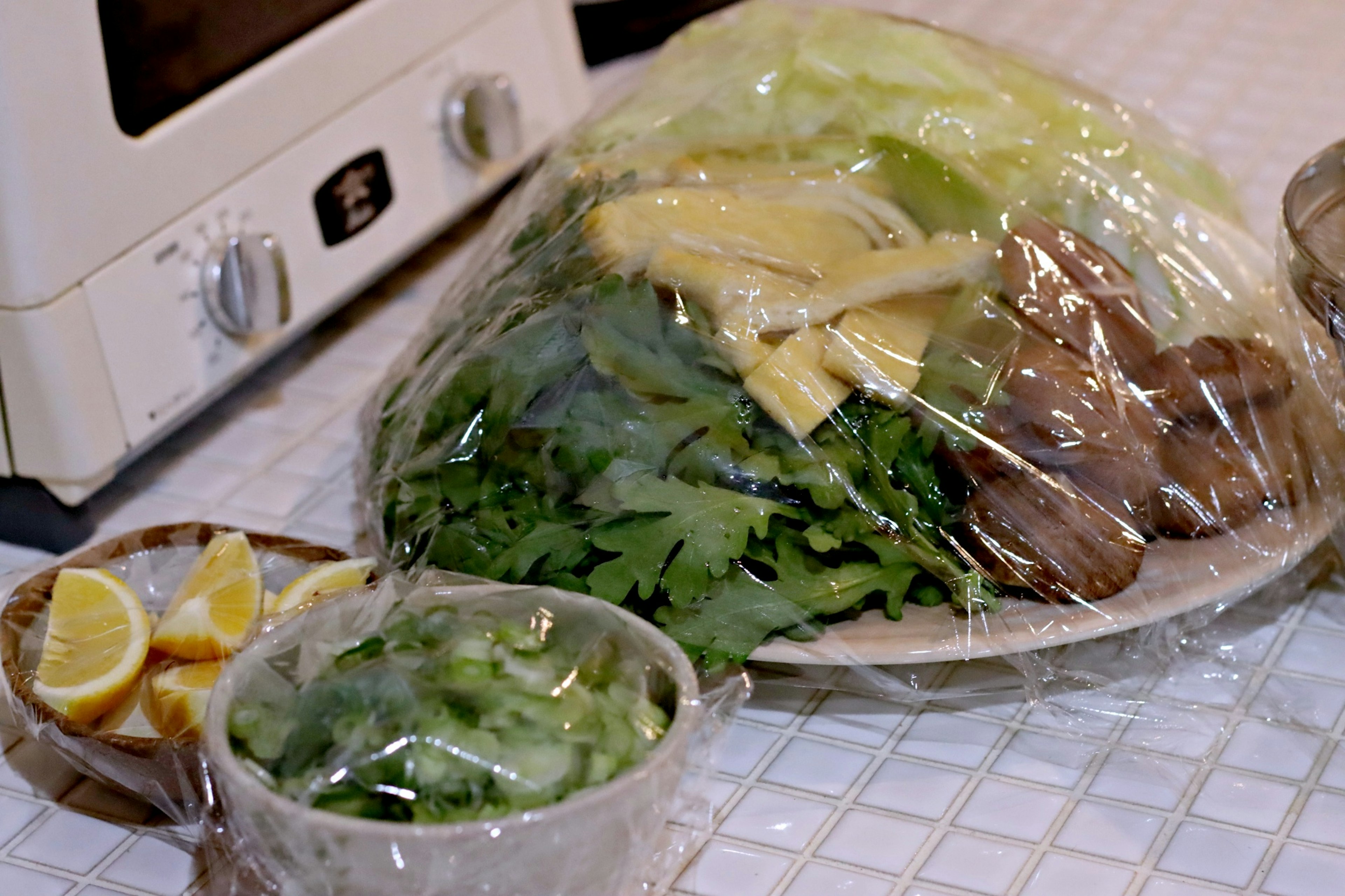 A plate of fresh vegetables and herbs wrapped in plastic film