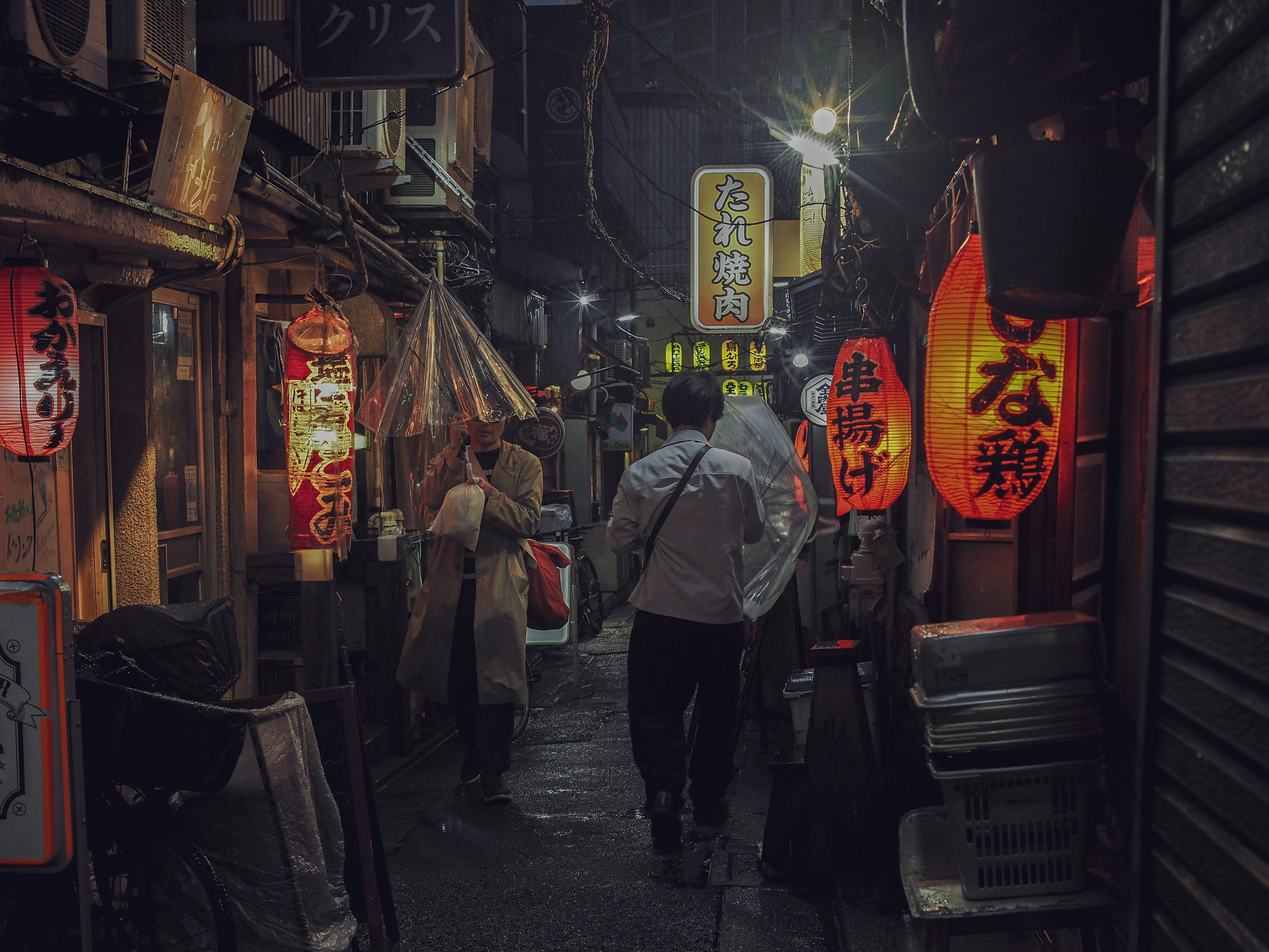 Narrow alley illuminated by vibrant lanterns and bustling people