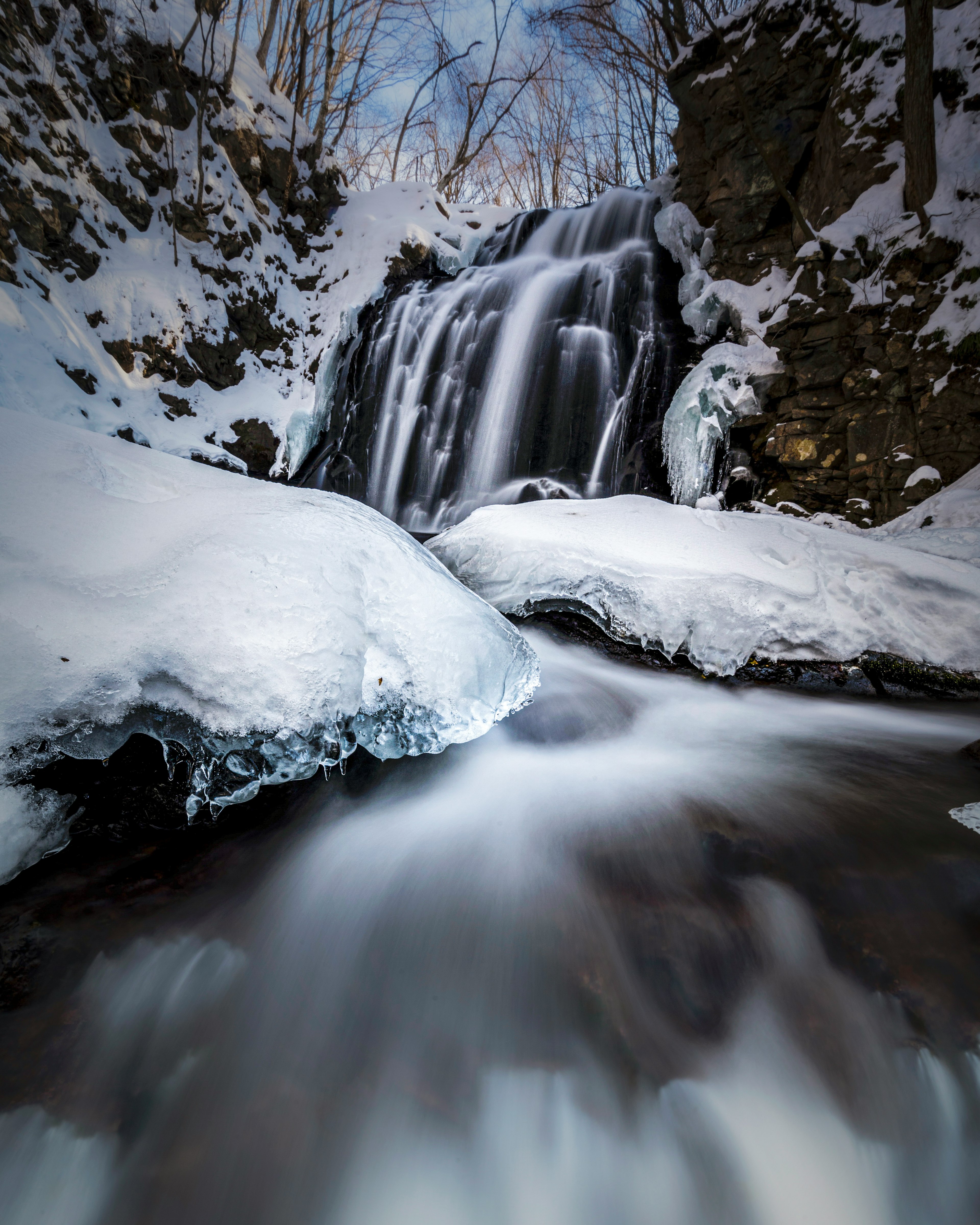 Bellissimo scenario di una cascata e acqua che scorre coperta di neve