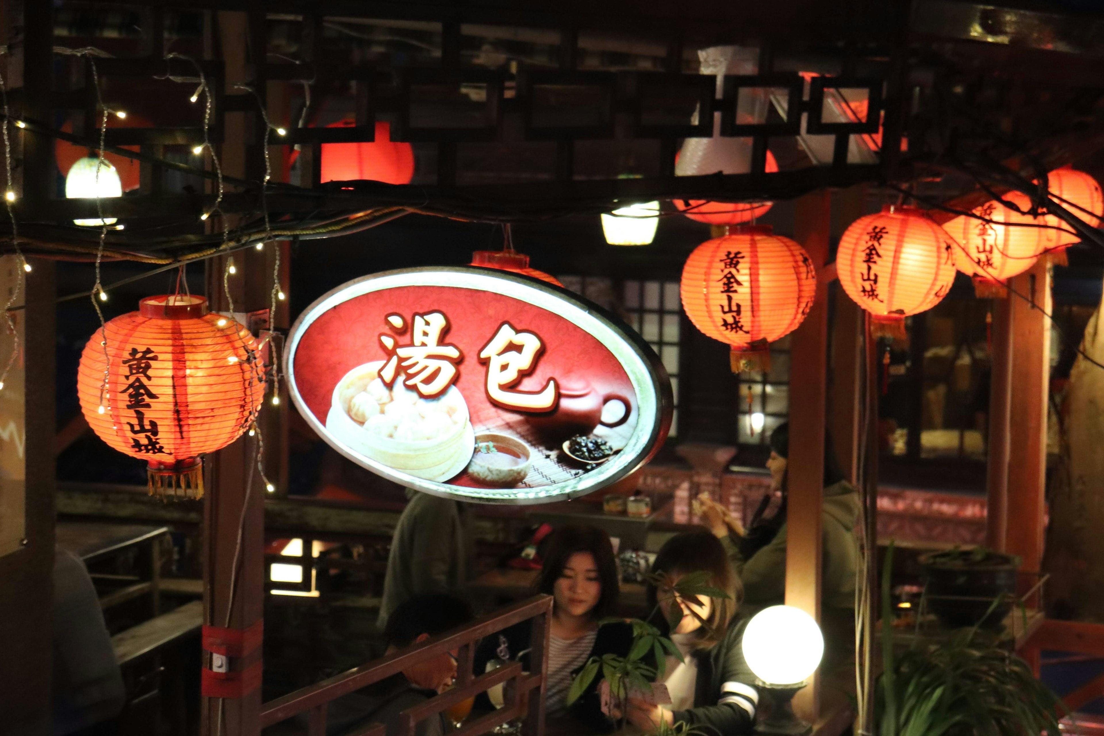 Night scene of an outdoor restaurant with lanterns and a sign