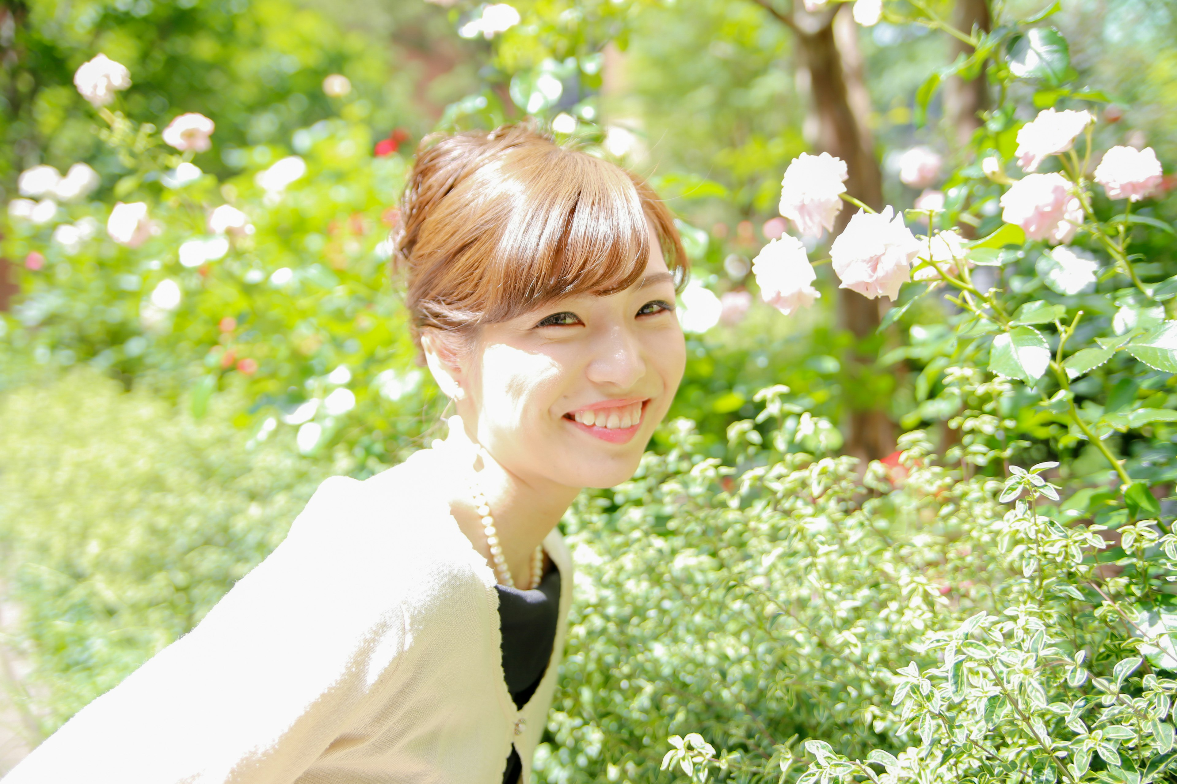 Mujer sonriente en un jardín verde con hermosas rosas