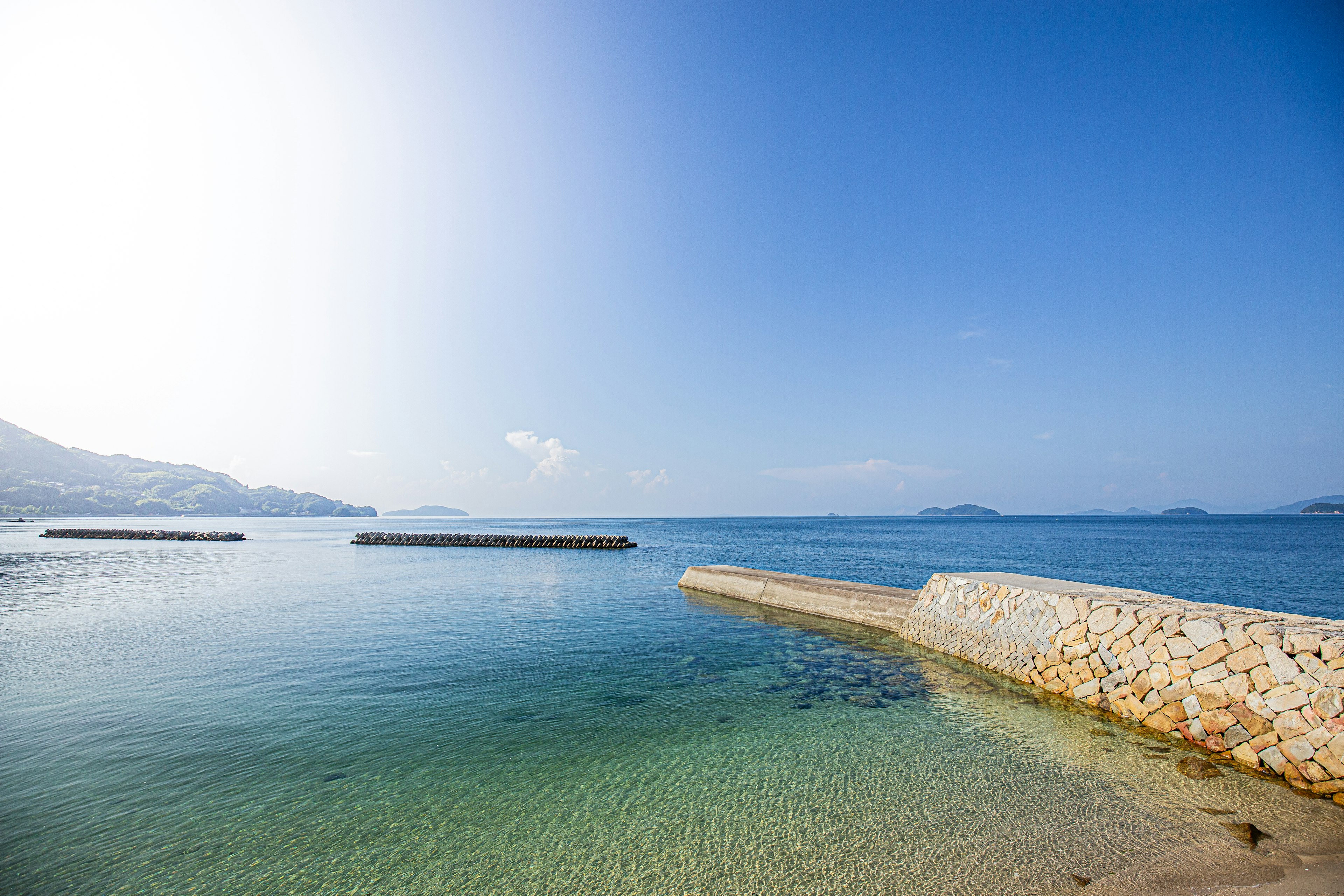 Scenic view of blue sea and sky with visible harbor breakwater