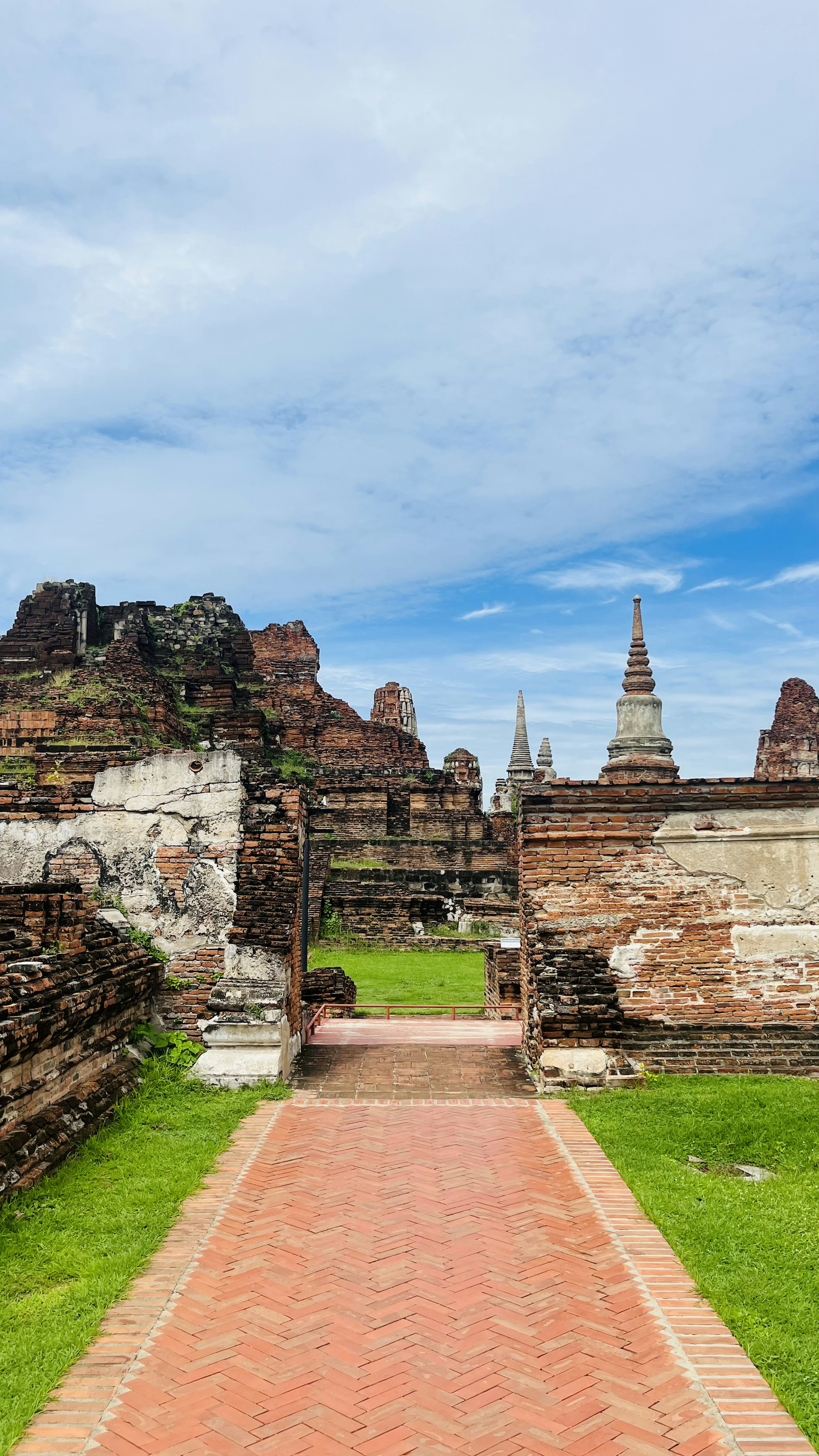 古代の遺跡と青空が広がる緑の草地に沿った歩道