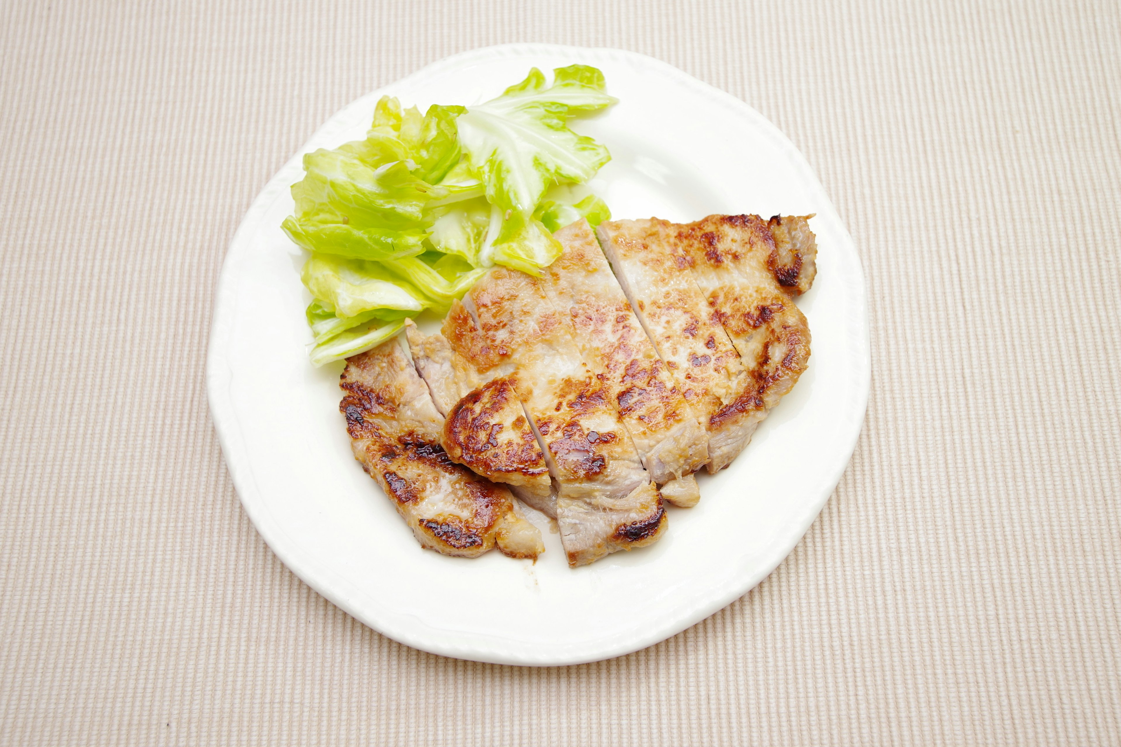 Grilled meat served on a white plate with fresh celery