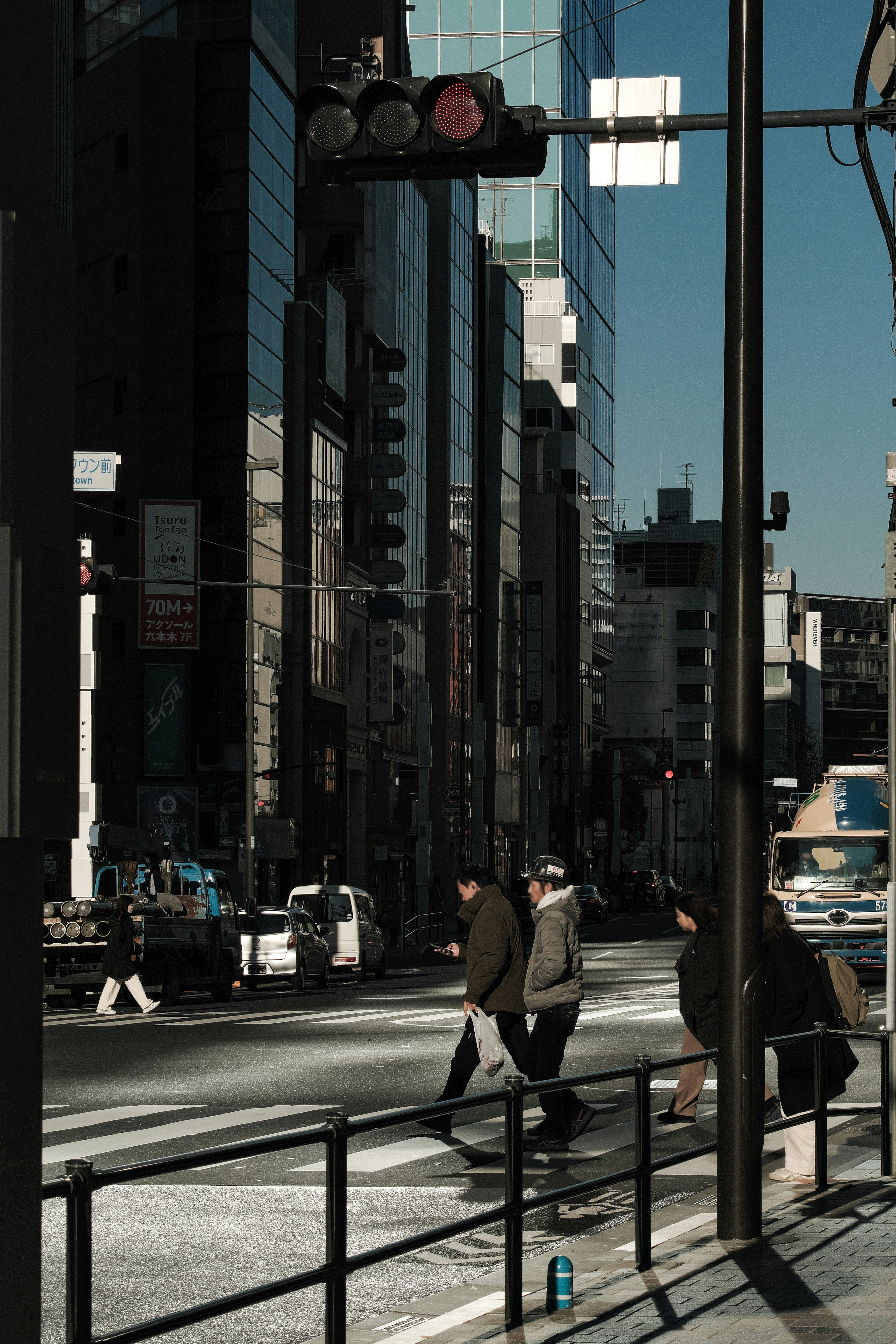 ビルが立ち並ぶ街中で信号を待つ人々