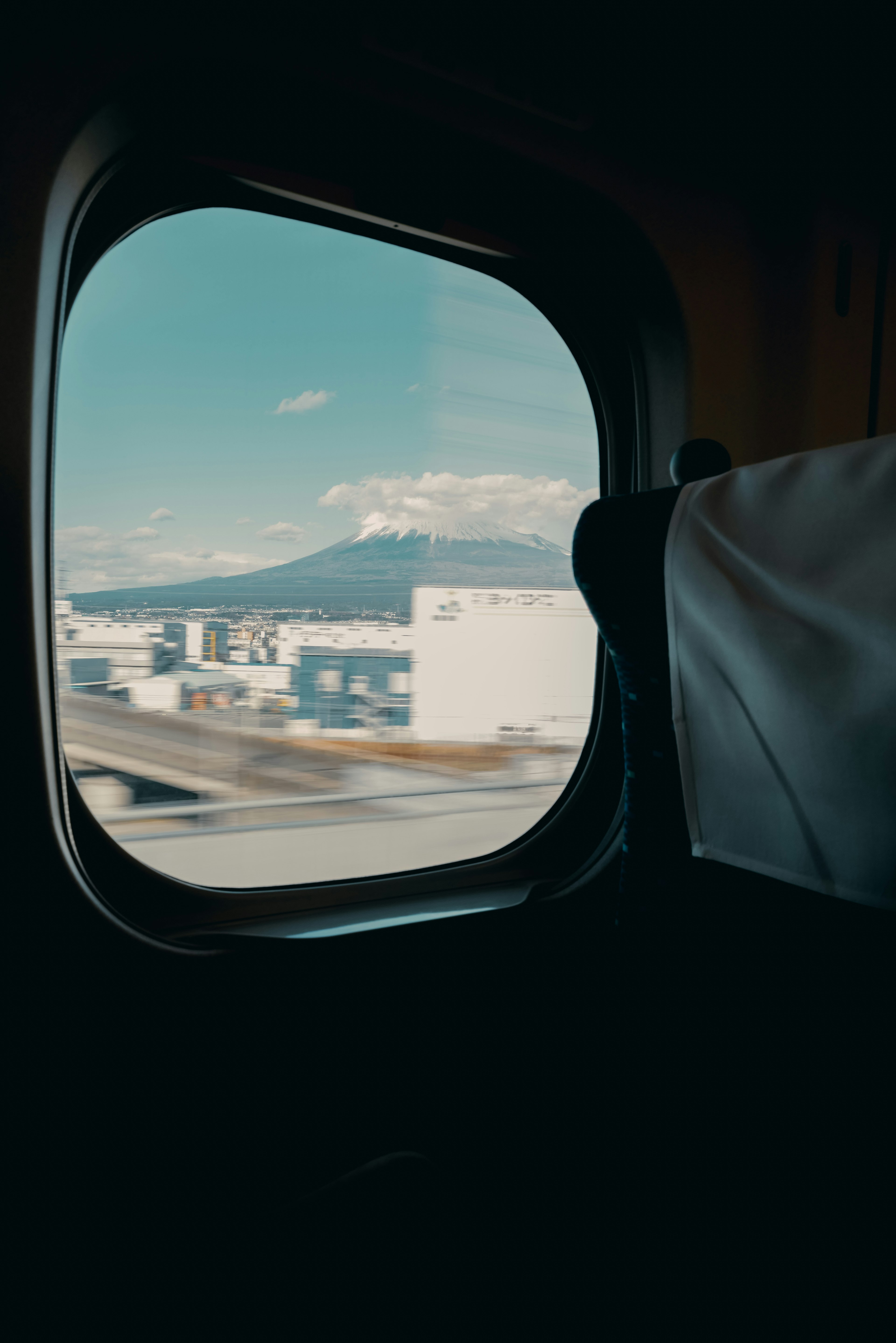 Blick auf einen Berg und blauen Himmel aus einem Flugzeugfenster