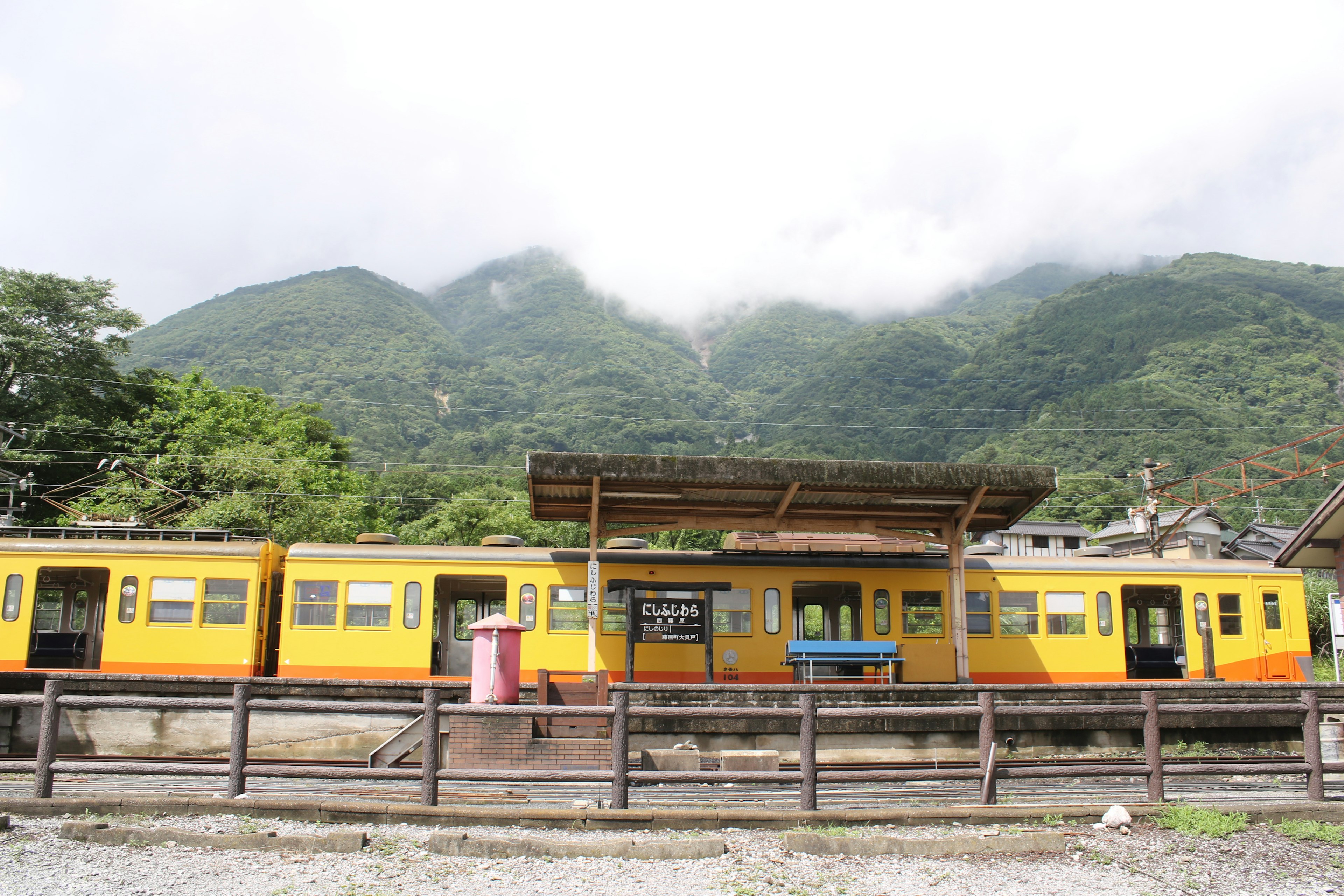 黄色の列車が山の背景に停車している駅の風景