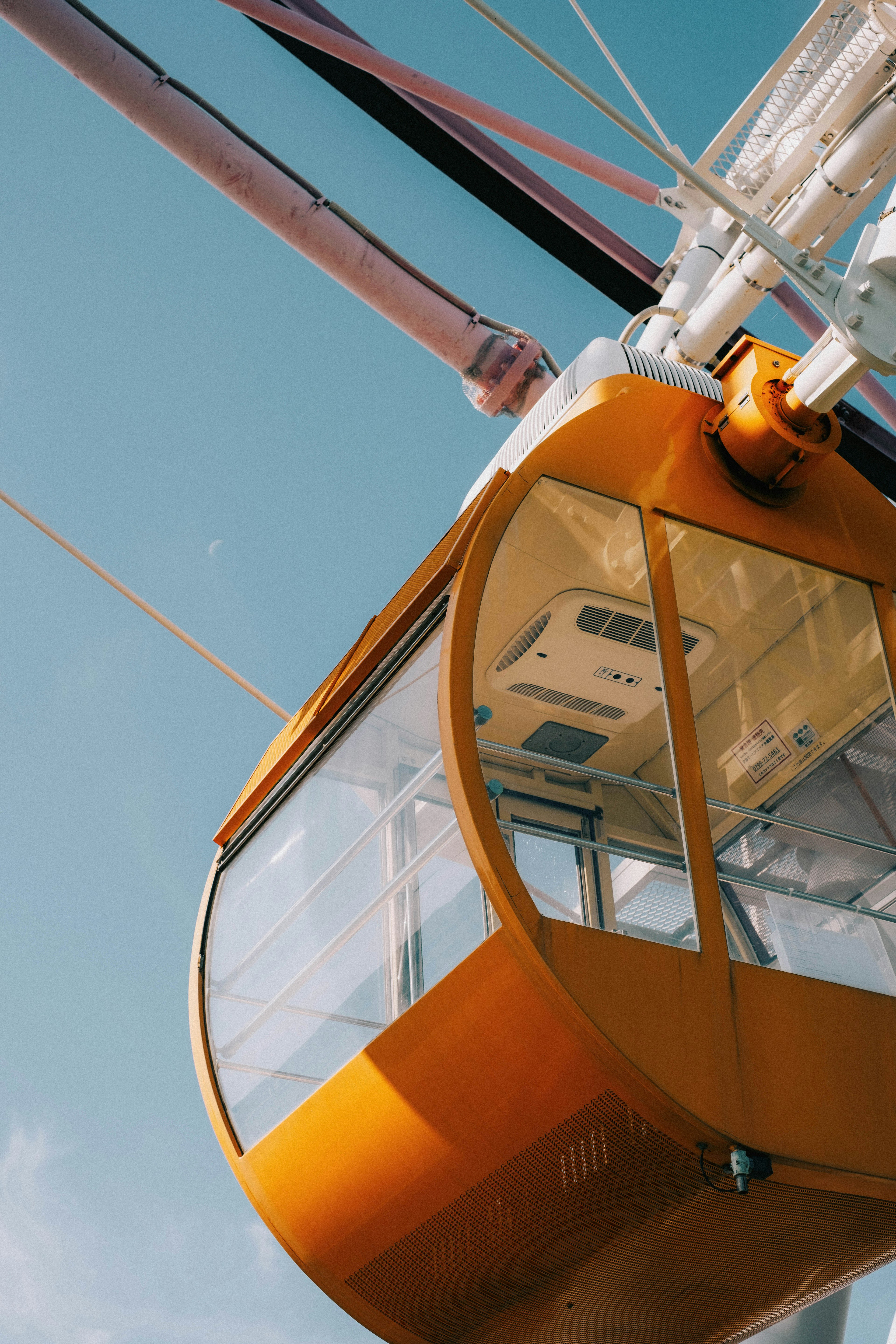 Kabin roda ferris oranye di latar belakang langit biru