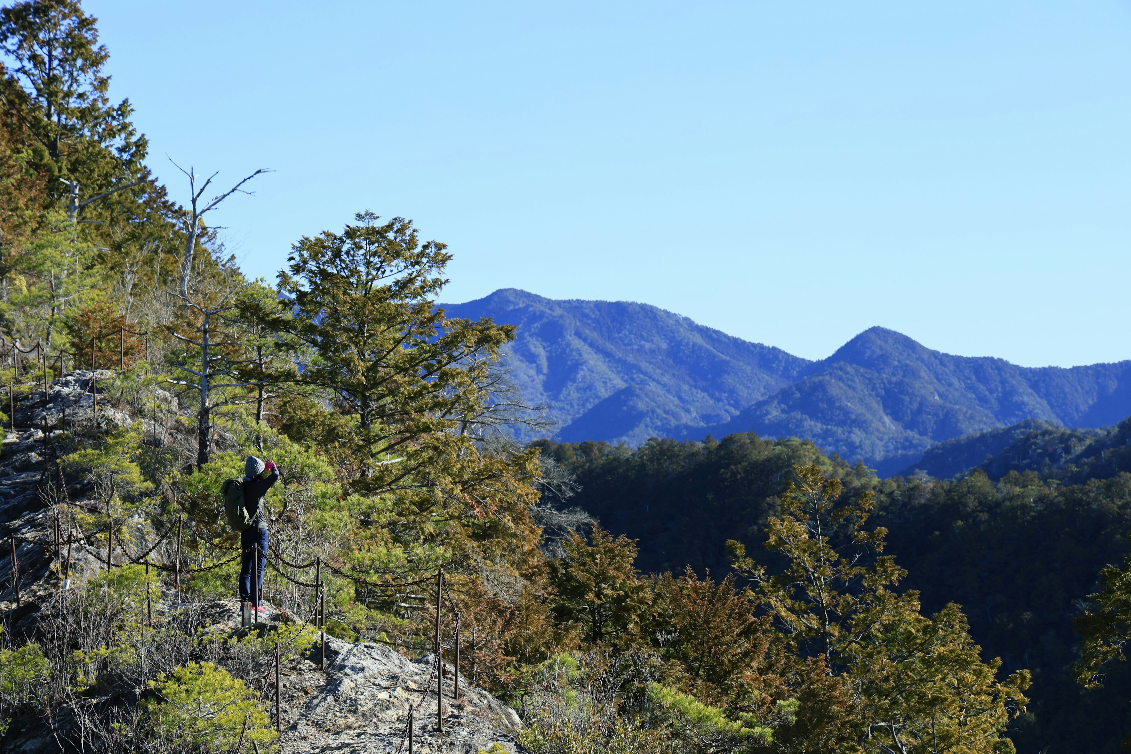 山の上に立つ人物と青空の風景