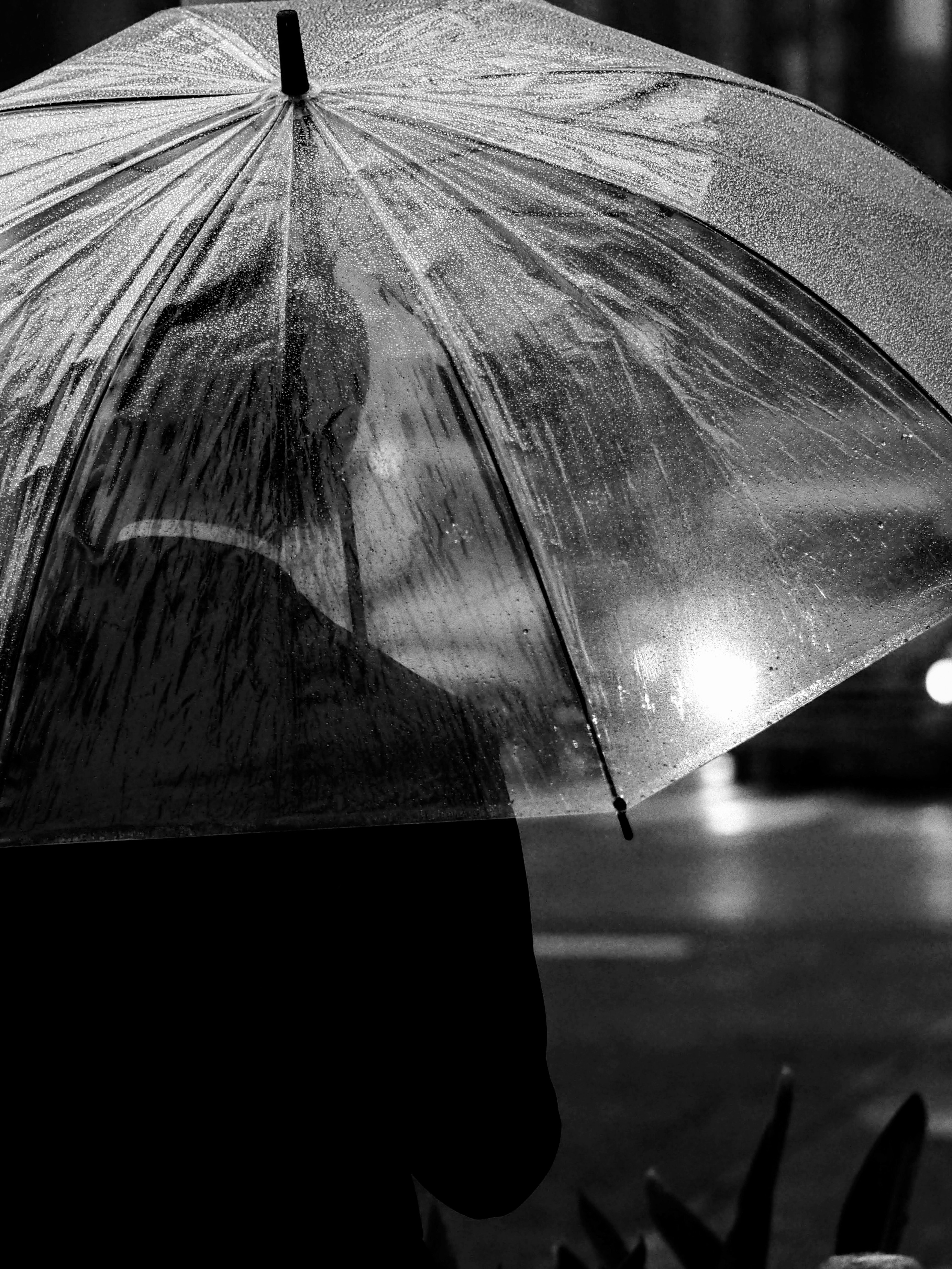 Siluette eines Mannes mit einem Regenschirm im Regen auf einer Stadtstraße