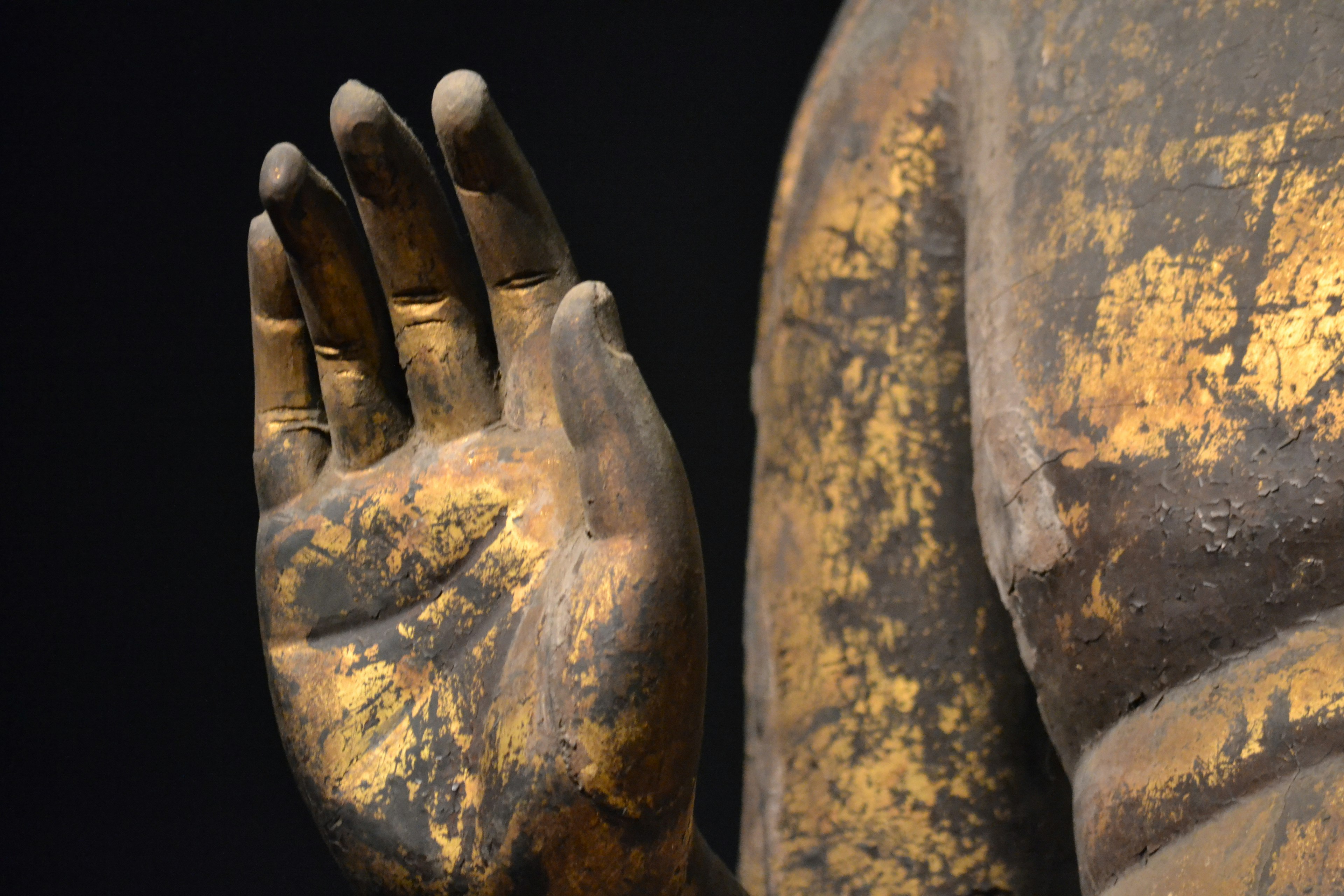 Detailed view of a golden Buddha statue hand with intricate features