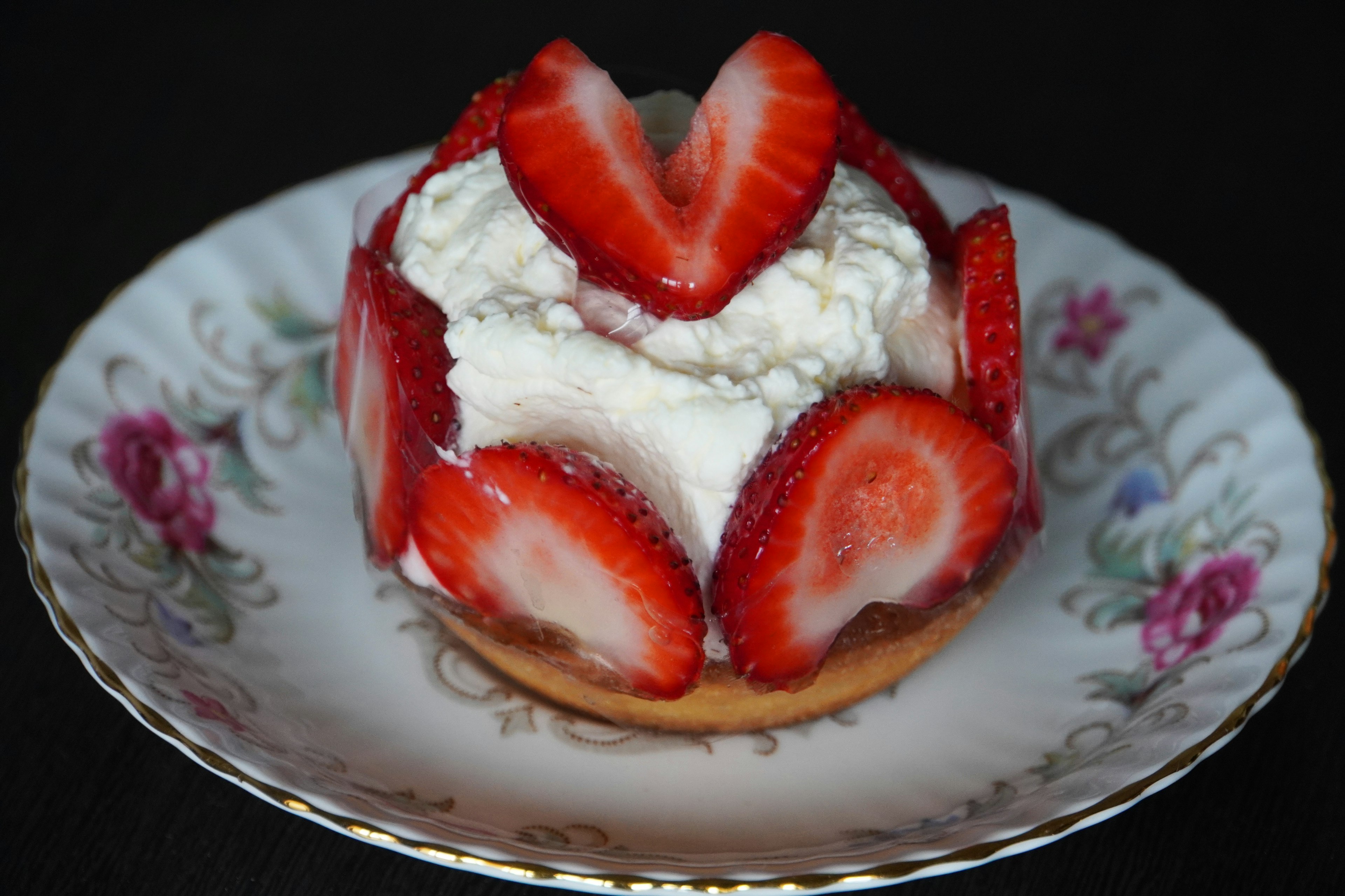 A dessert topped with strawberries and whipped cream on a decorative plate