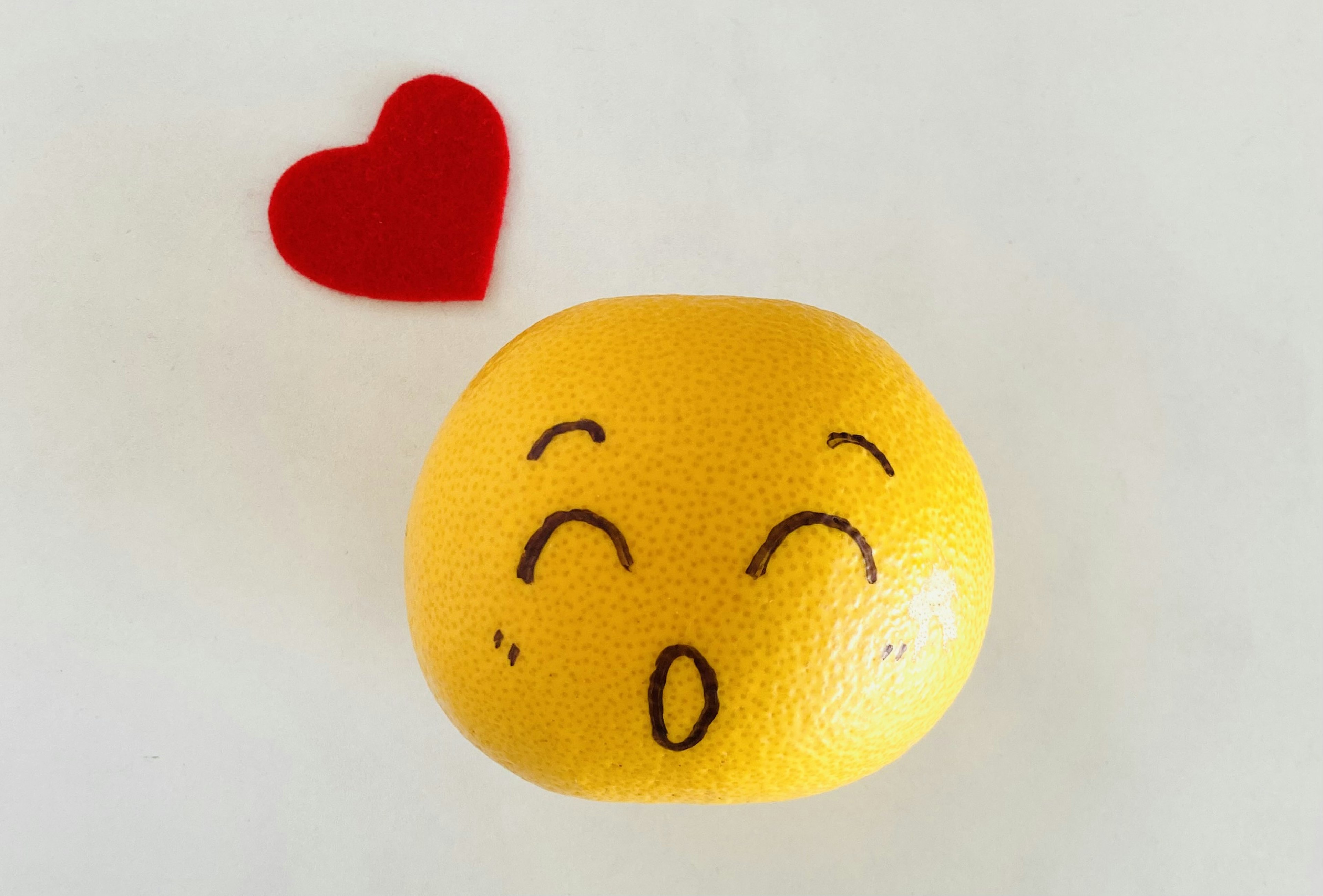 Yellow fruit with a happy face expression and a red heart shape