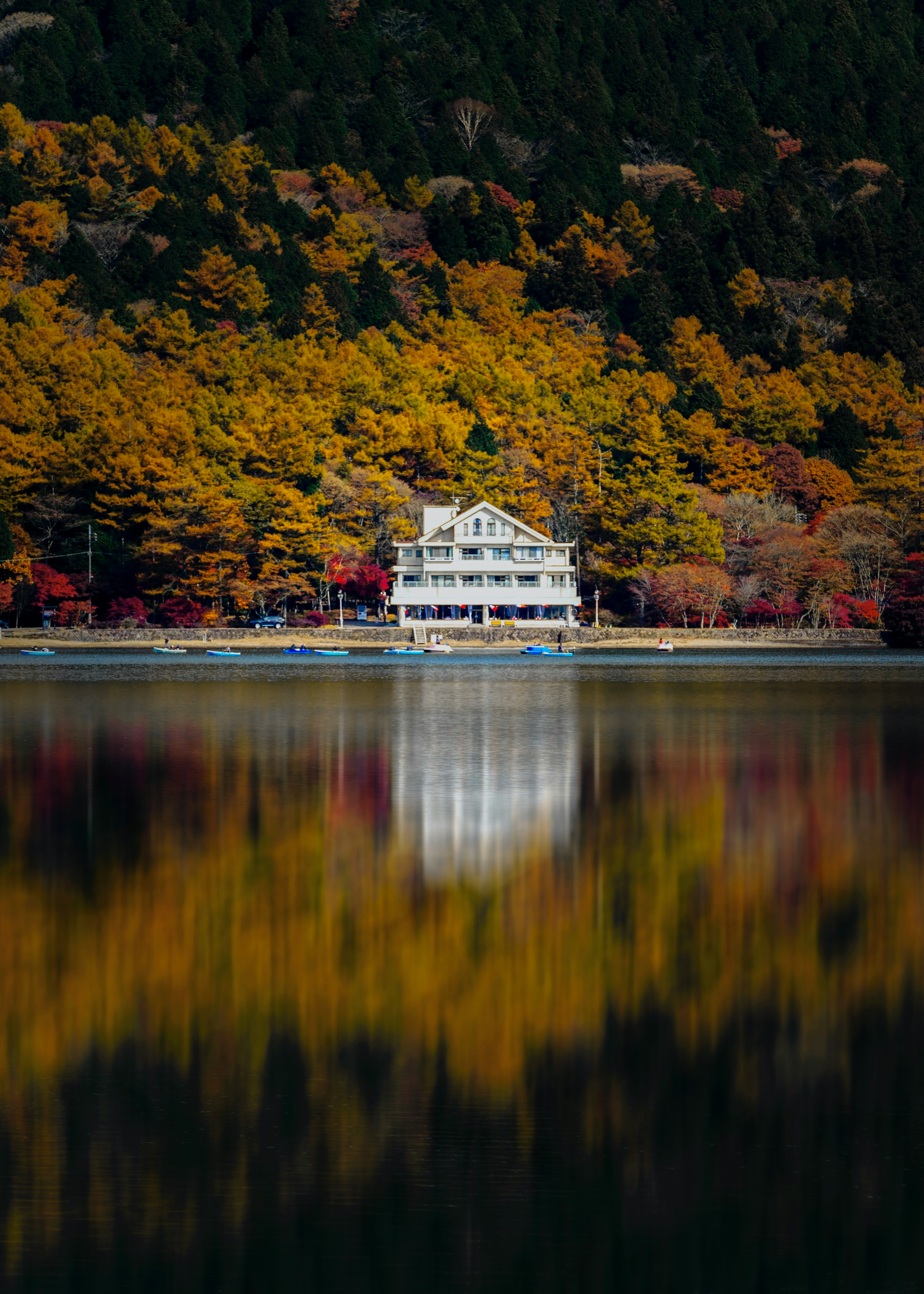 White house by a serene lake surrounded by autumn foliage