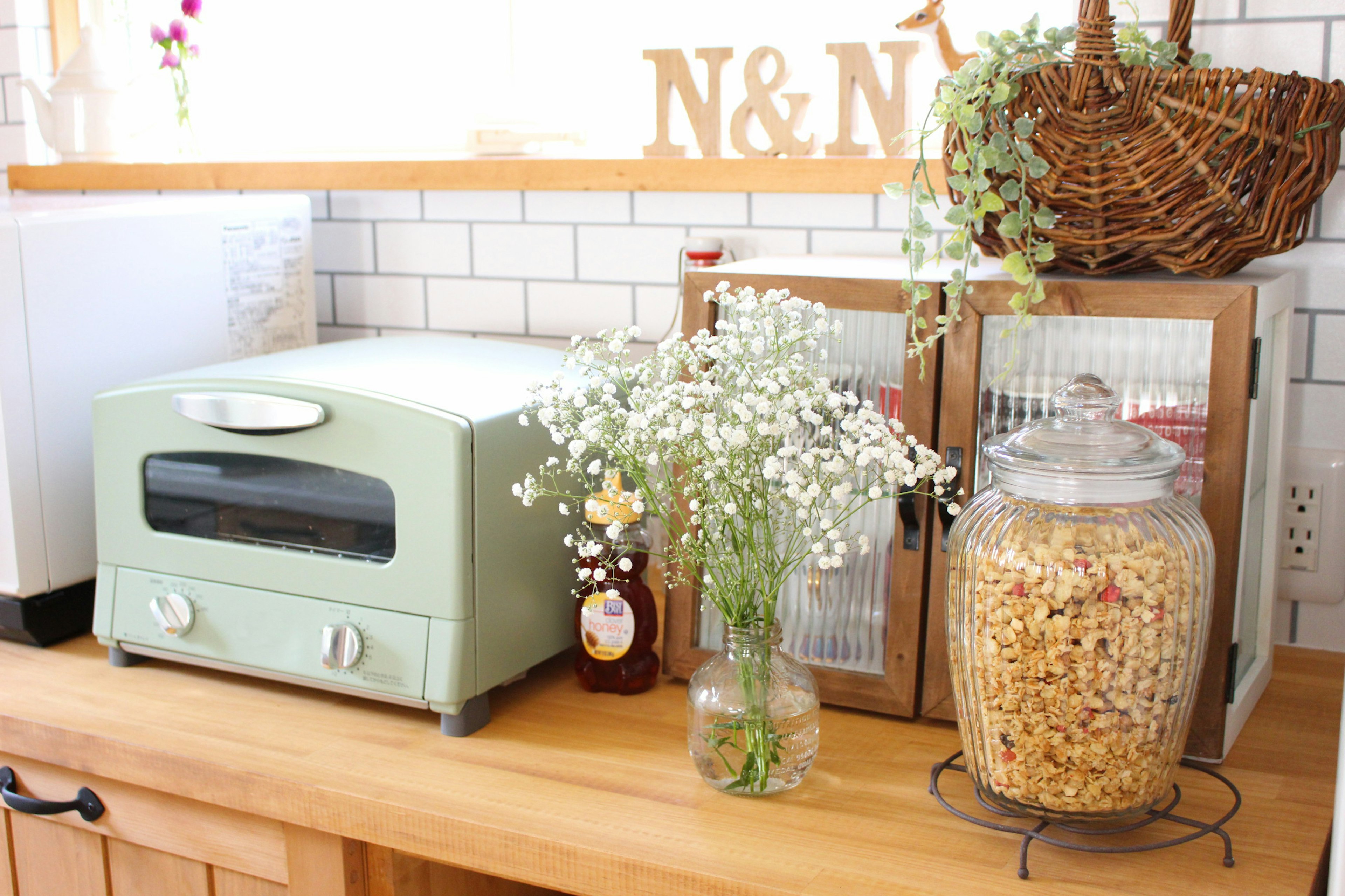 Image of a mint green toaster with a vase of baby breath flowers on a kitchen counter