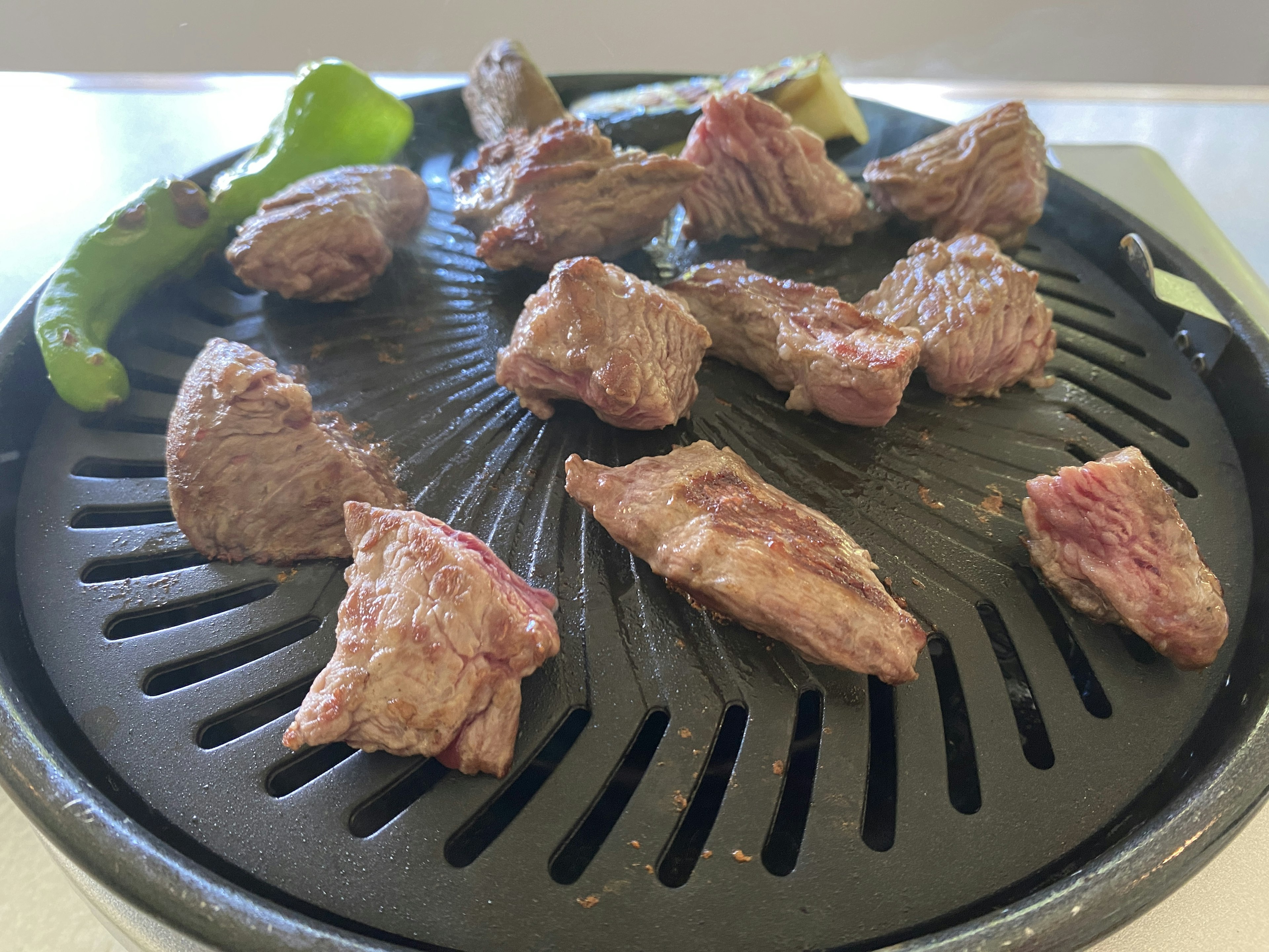 Piezas de carne a la parrilla en una parrilla con pimientos verdes