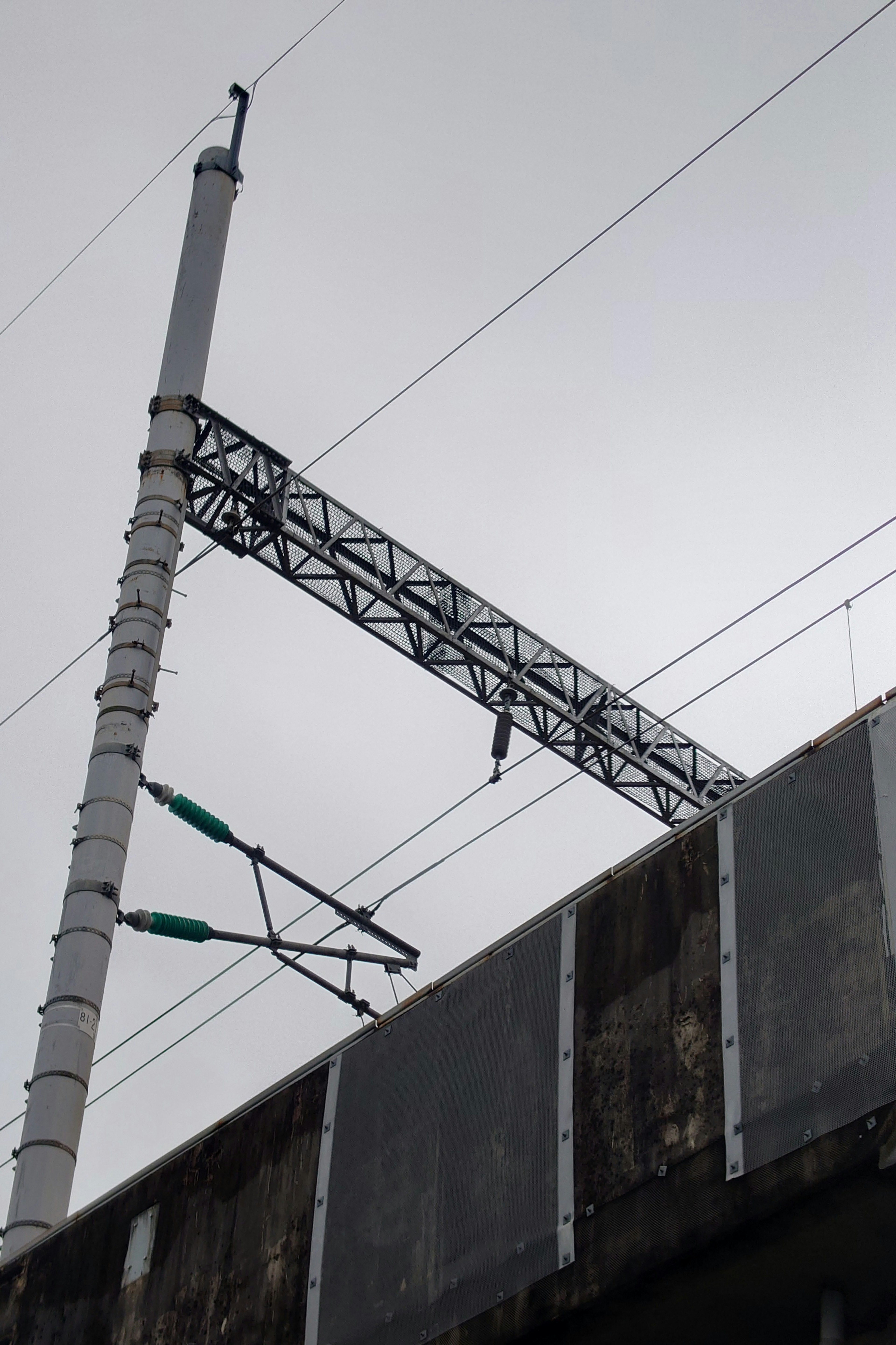 Poteau ferroviaire élevé avec des lignes aériennes sous un ciel nuageux