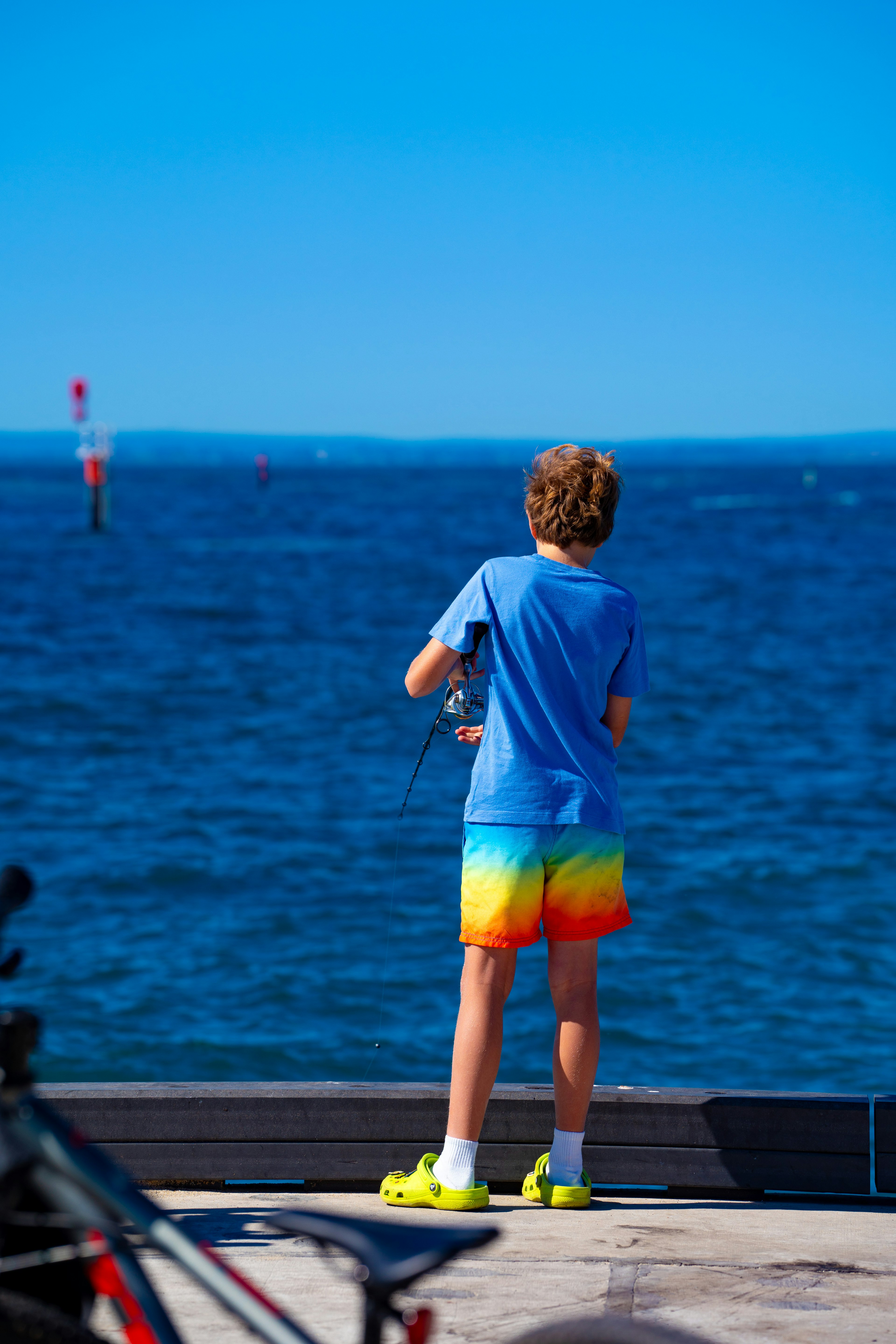 Junge schaut auf das Meer in bunten Shorts