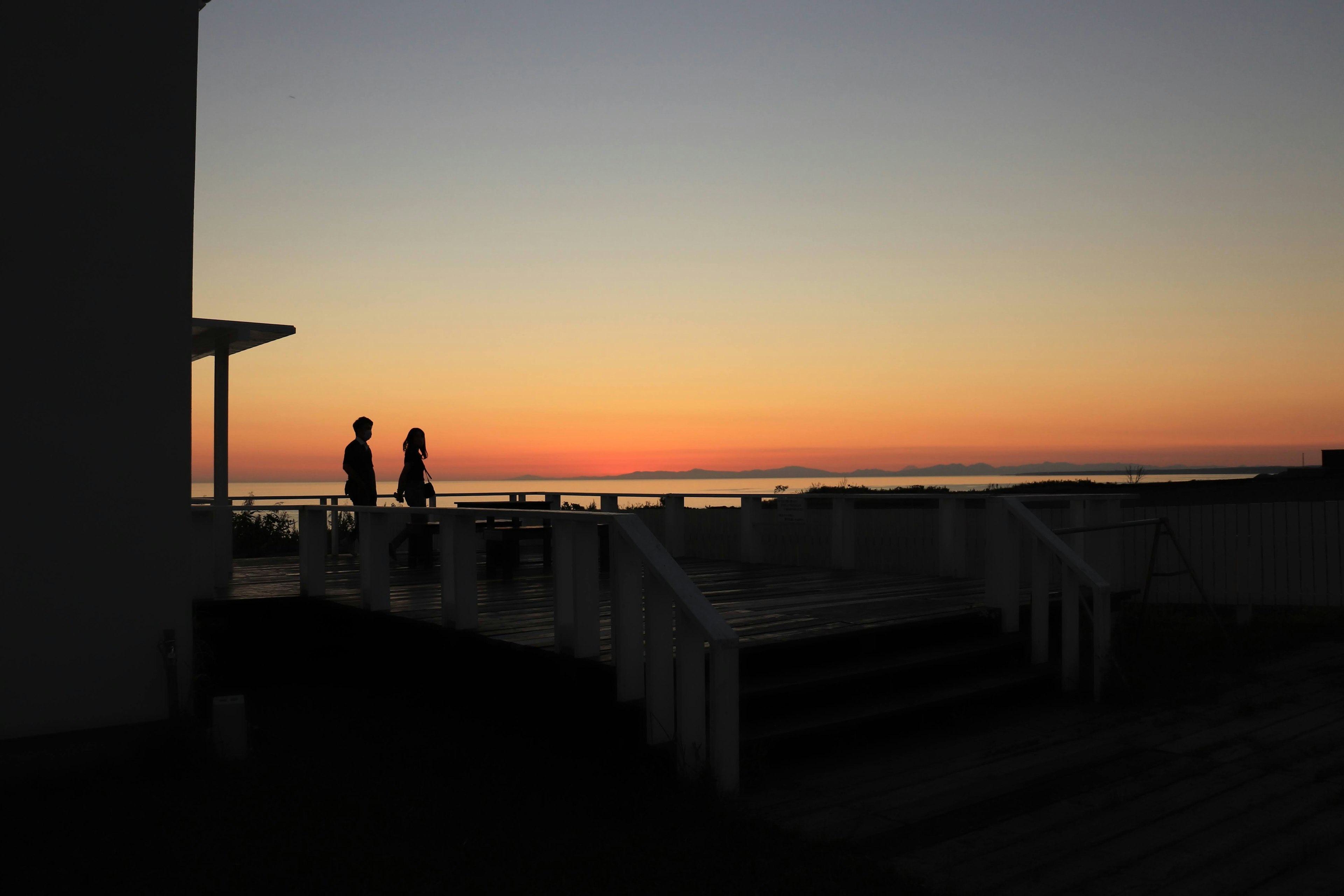 Silhouette di due persone contro un tramonto sul mare