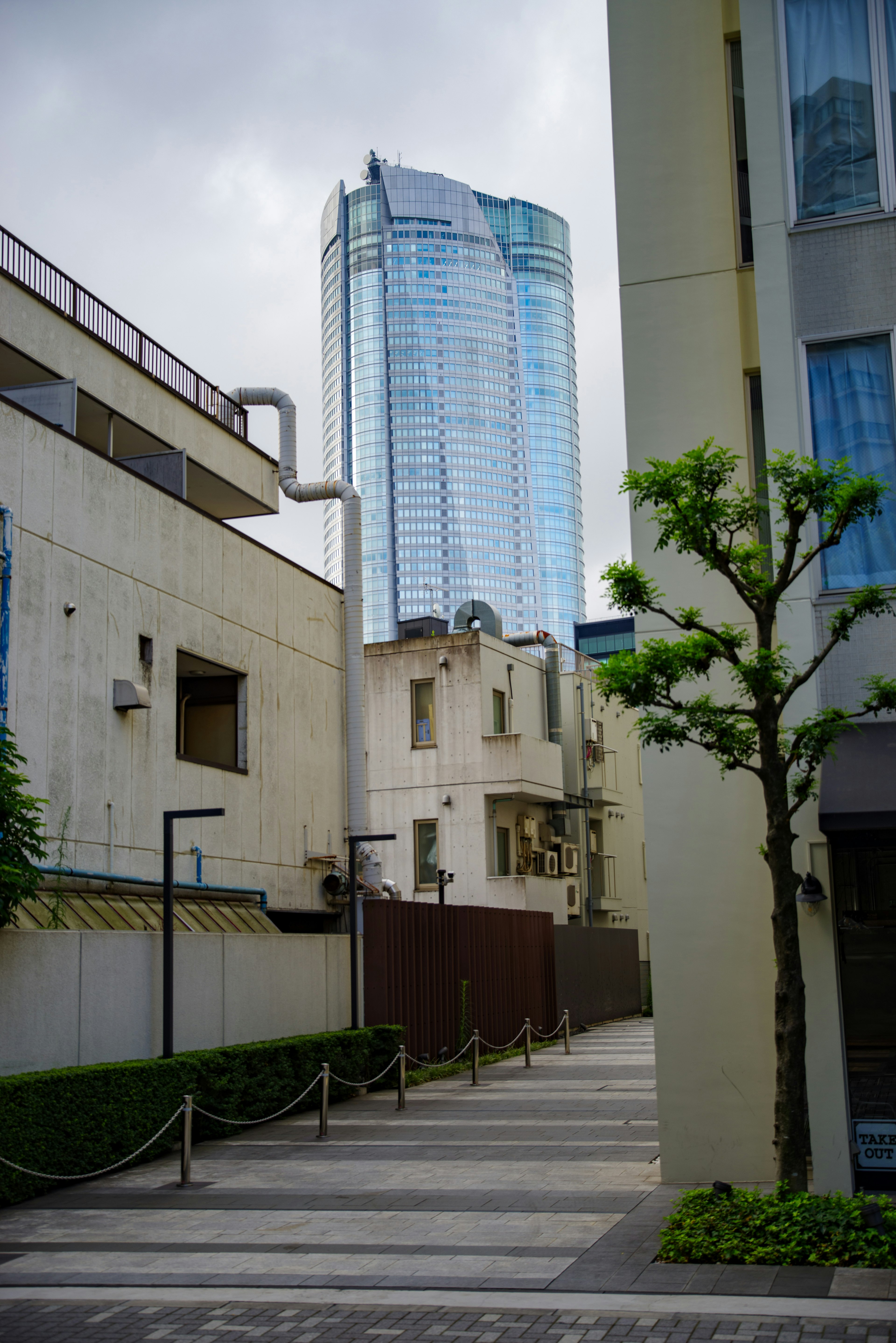 Vista di una strada stretta con un grattacielo moderno sullo sfondo che contrasta con edifici più antichi