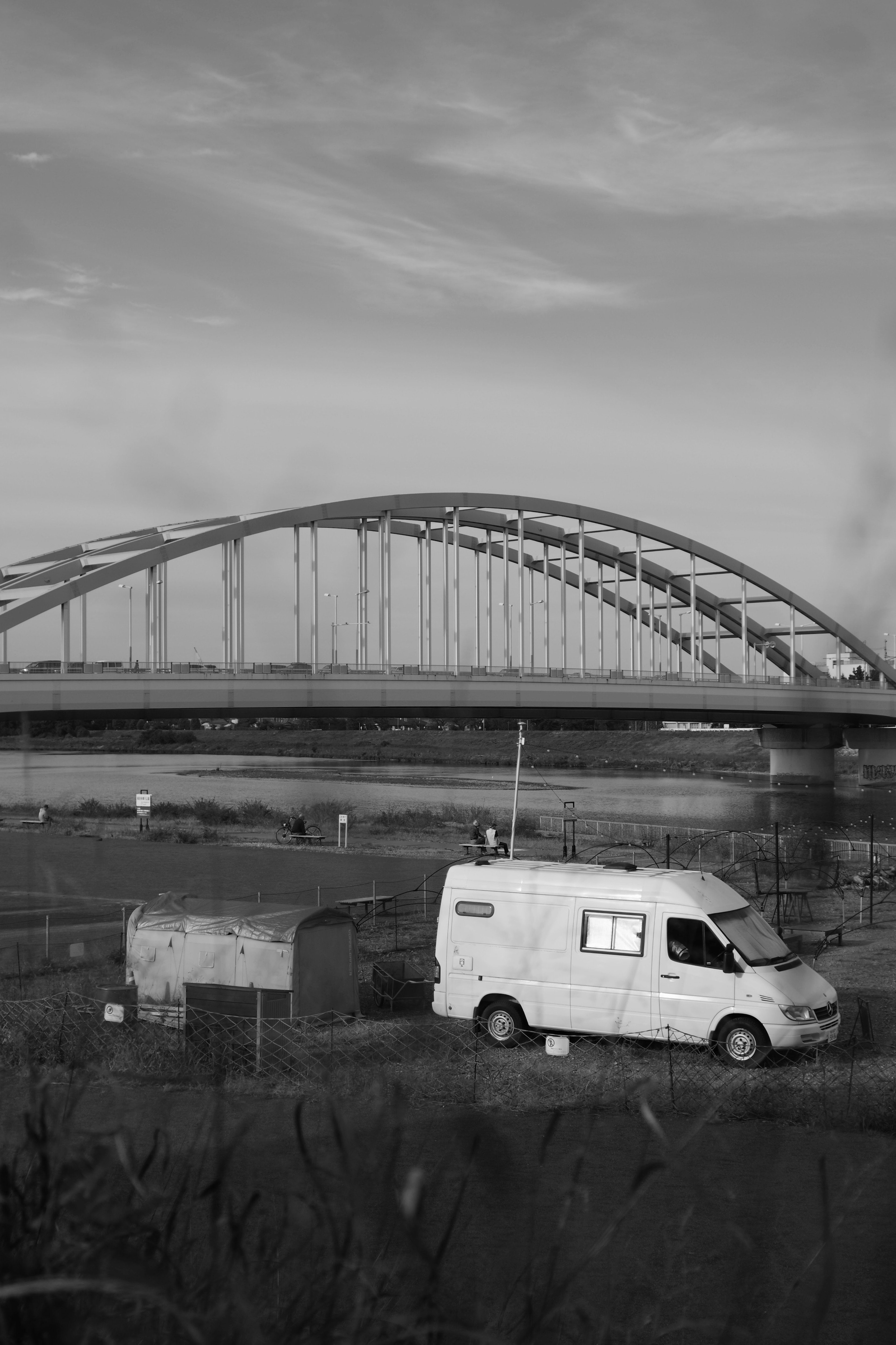 Scena in bianco e nero con un ponte e un furgone bianco