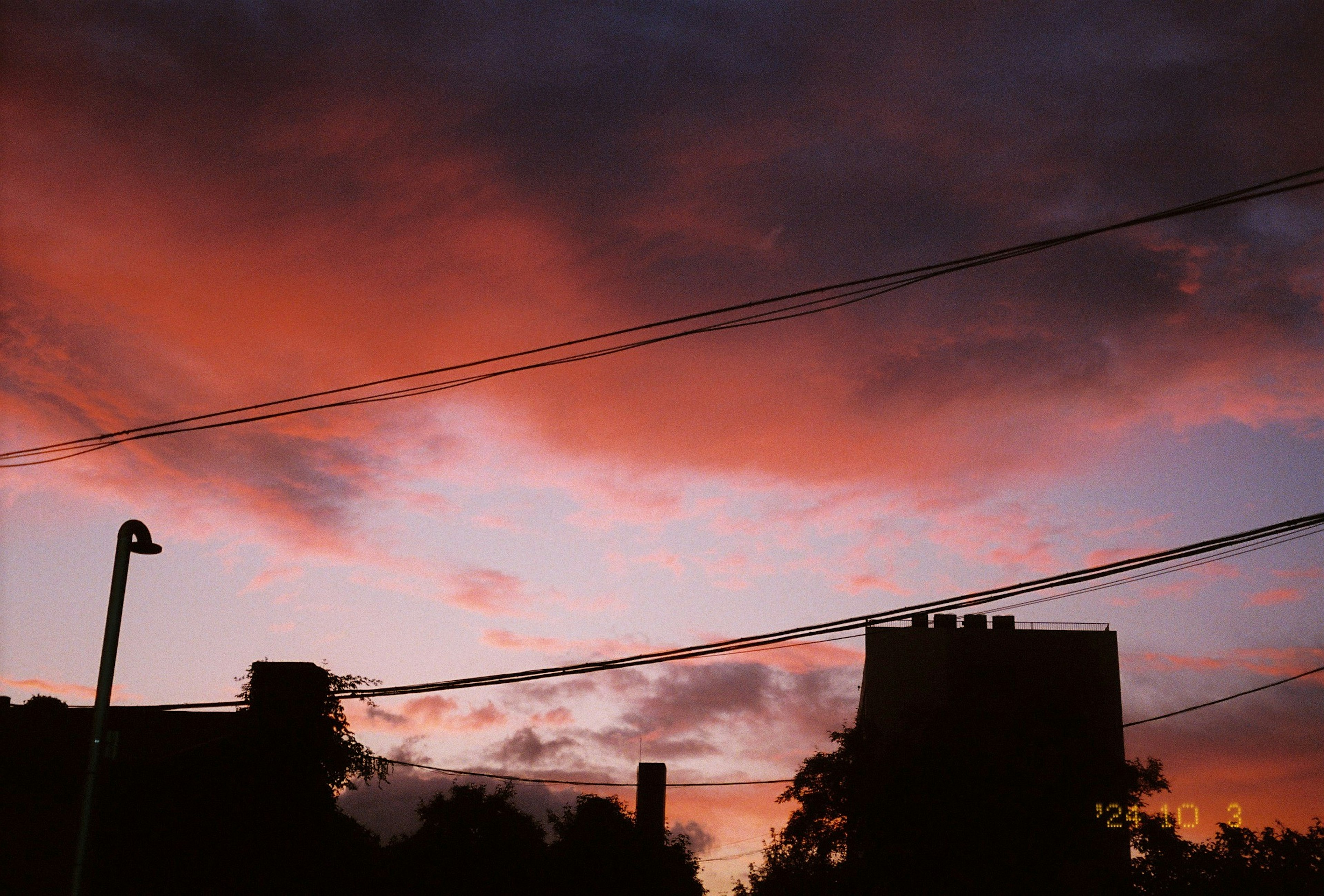 Edificios en silueta contra un vibrante cielo de atardecer con nubes naranjas y rosas