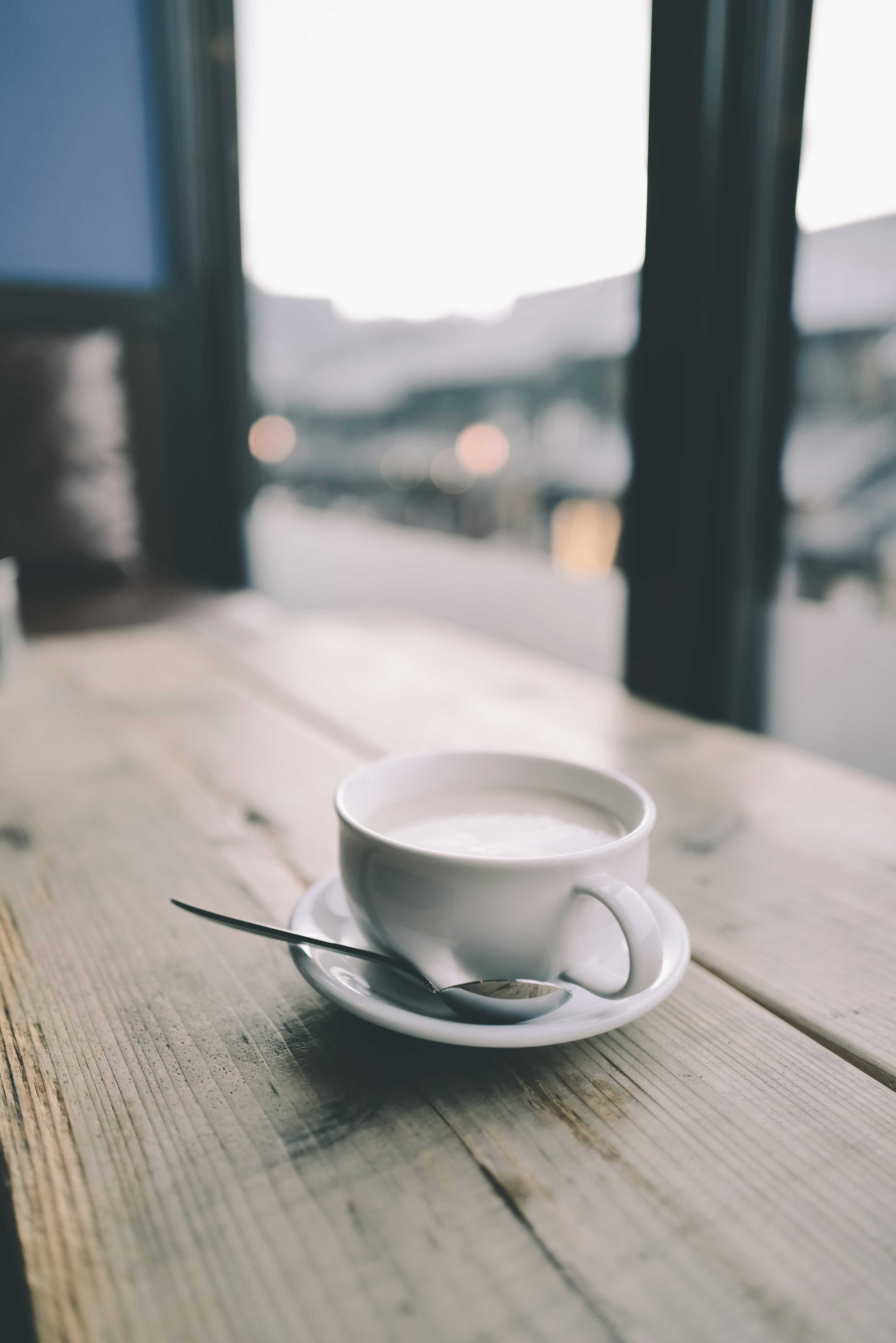 Eine weiße Tasse Kaffee auf einem Holztisch mit einem Löffel