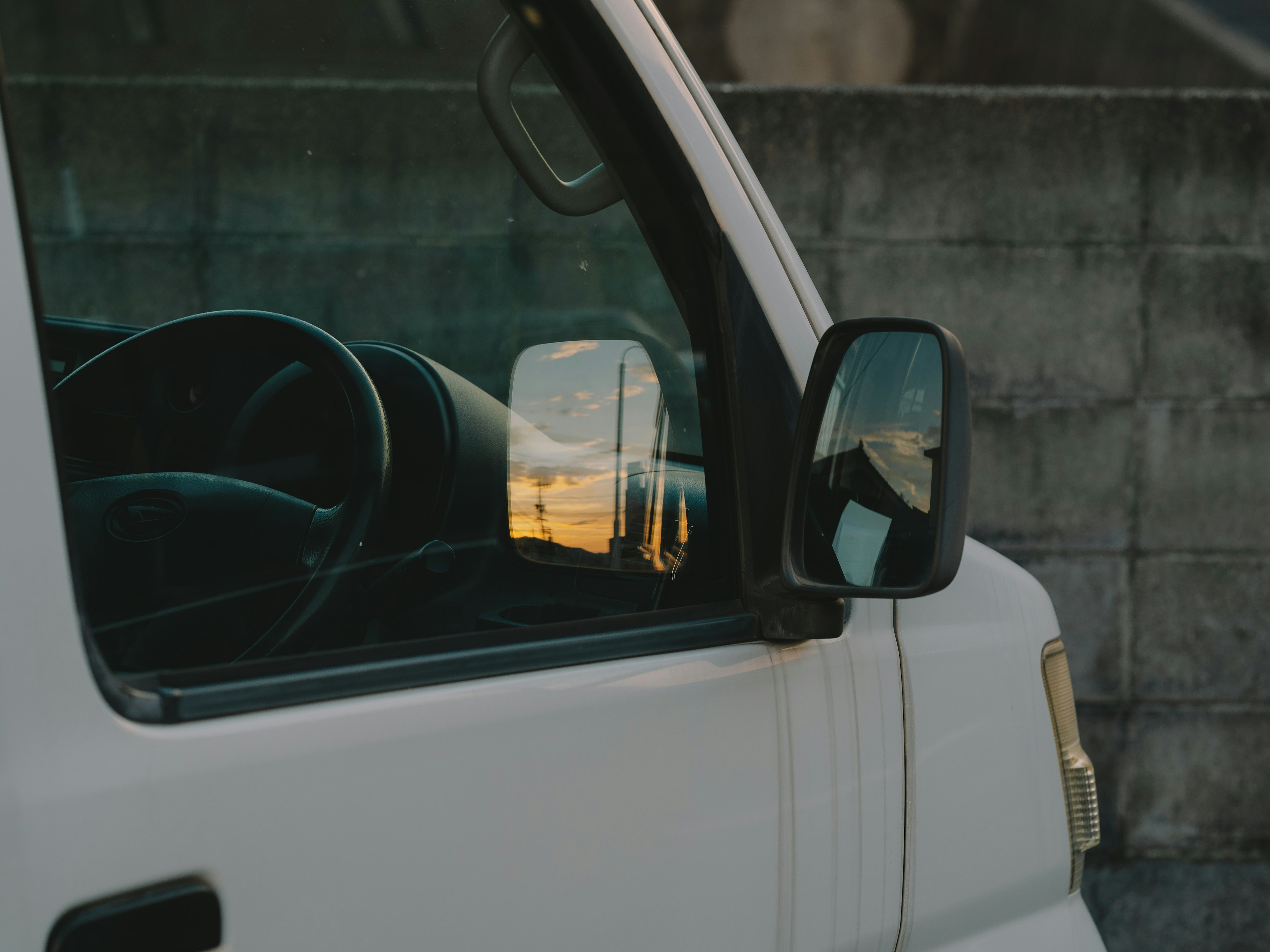 White van with reflection in the side mirror and steering wheel visible