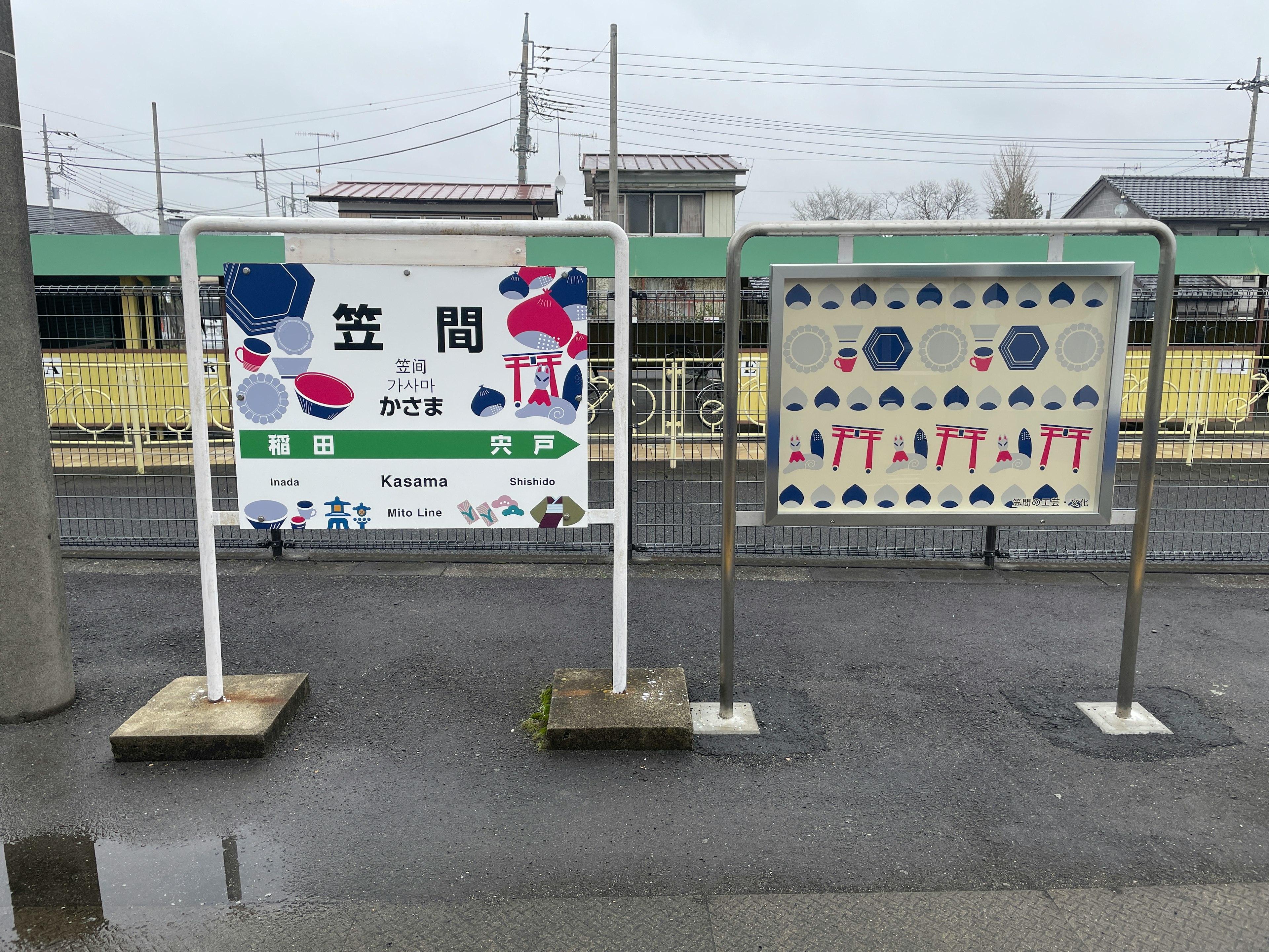 Zwei Schilder an einem Bahnhof mit bunten Designs und Stationsnamen