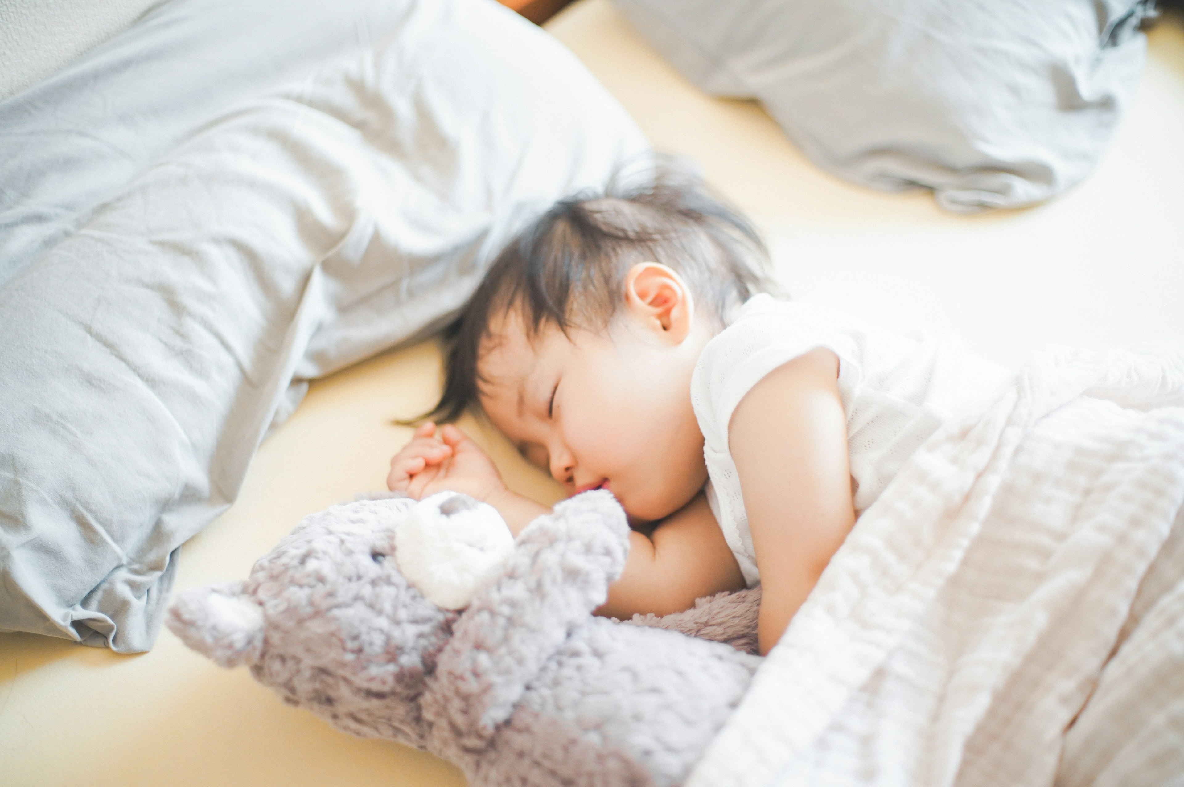 A child sleeping while hugging a teddy bear