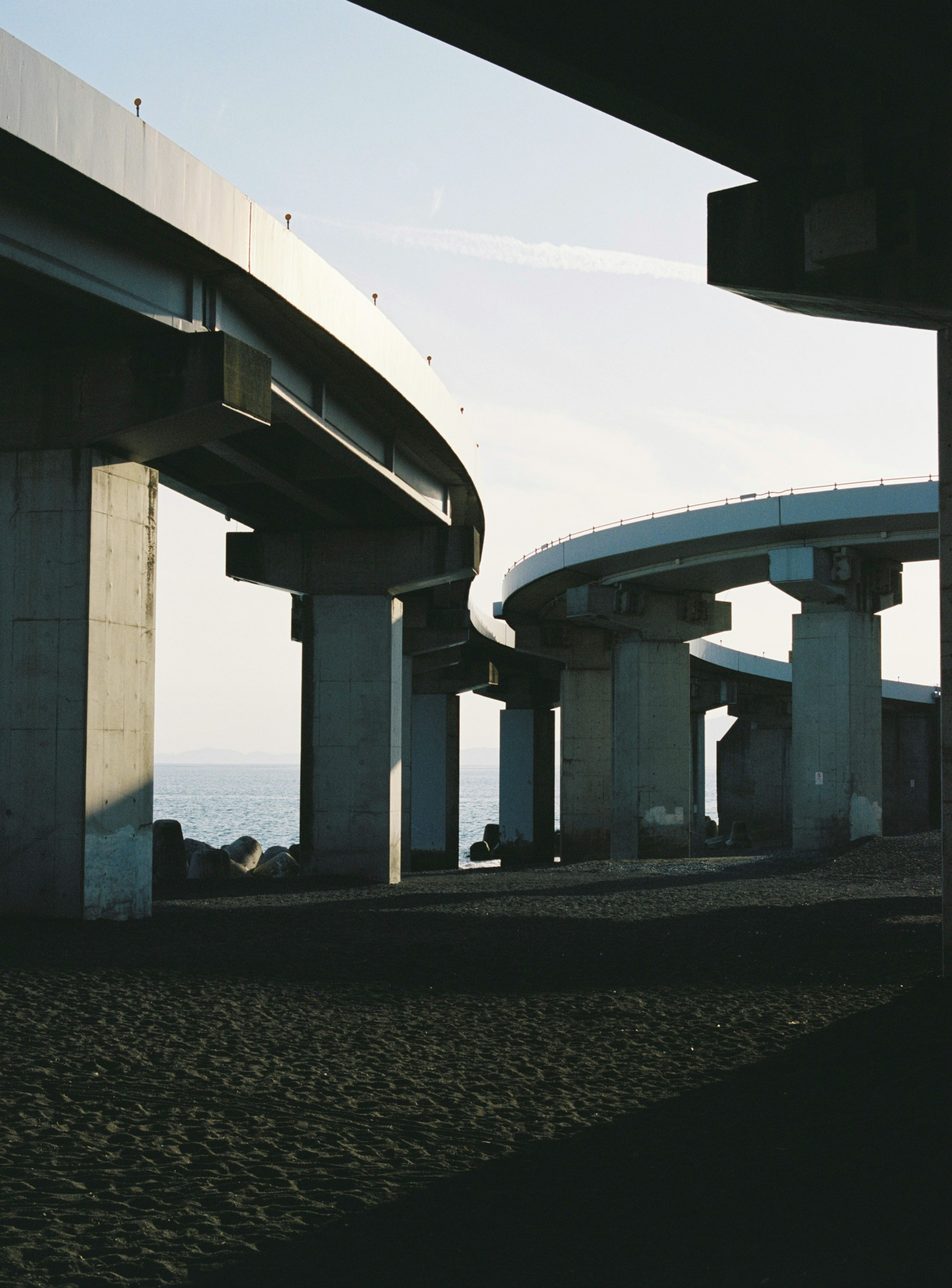 Kurvenförmige Überführungsstrukturen mit Betonpfeilern und einem sandigen Vordergrund