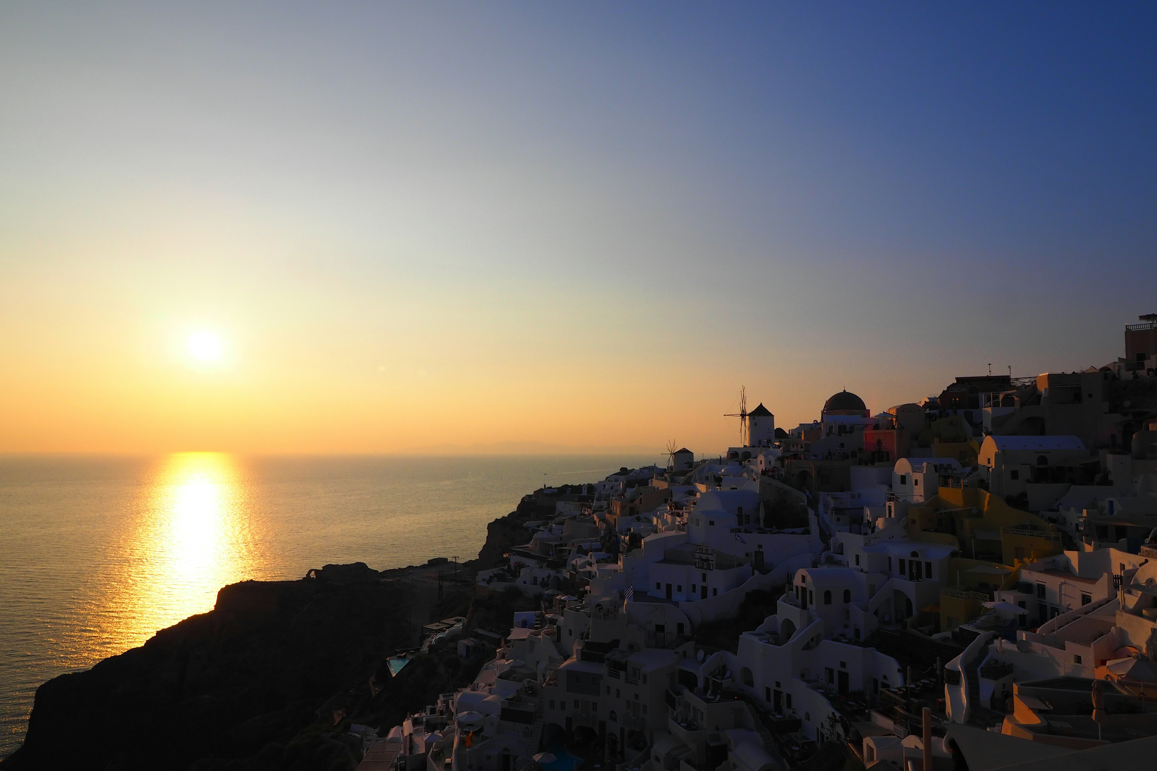 Hermoso atardecer sobre el mar en Santorini con edificios blancos en la colina