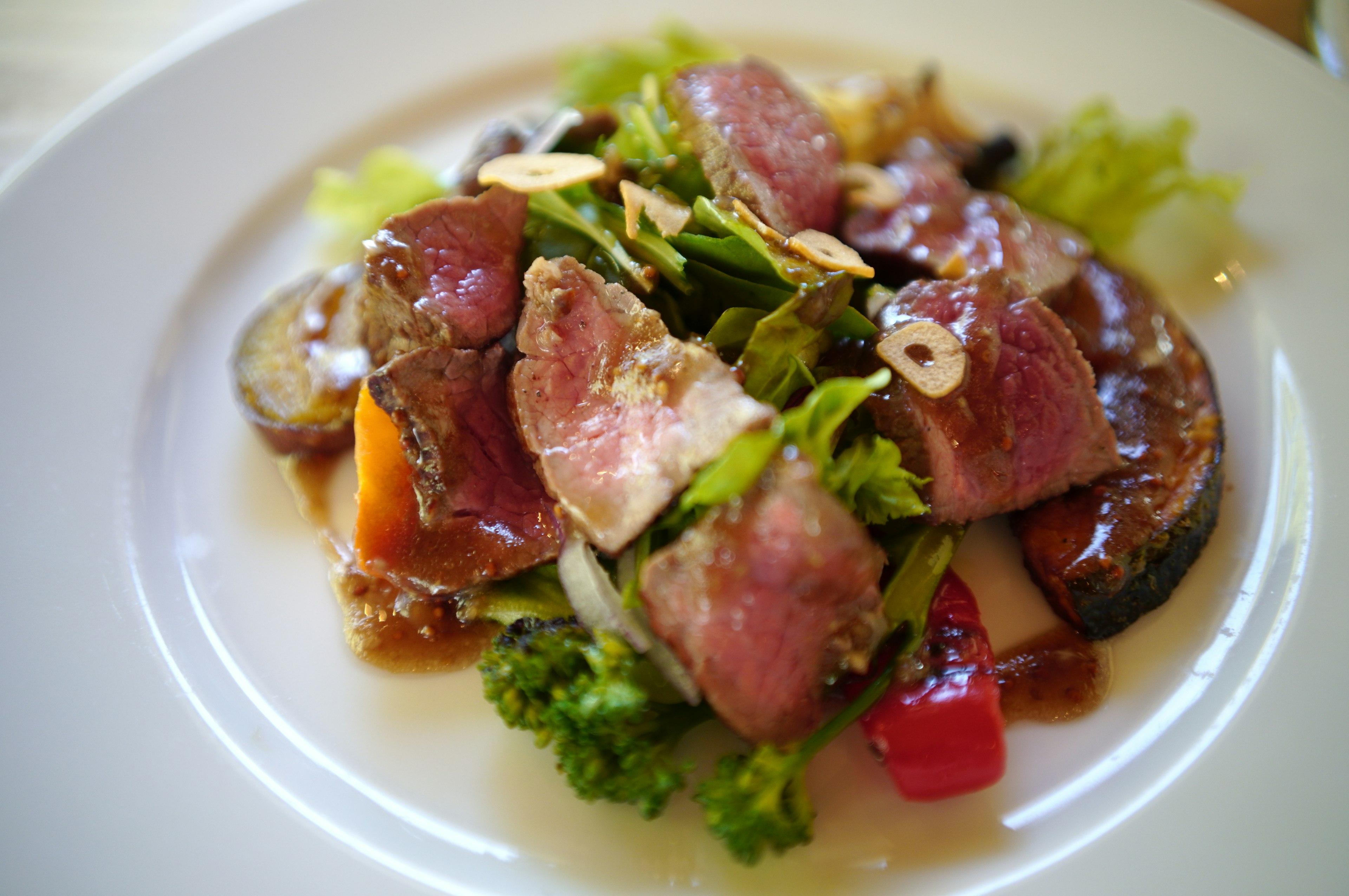 Plat de viande délicieux servi sur un lit de salade légumes vibrants et noix grillées incluses